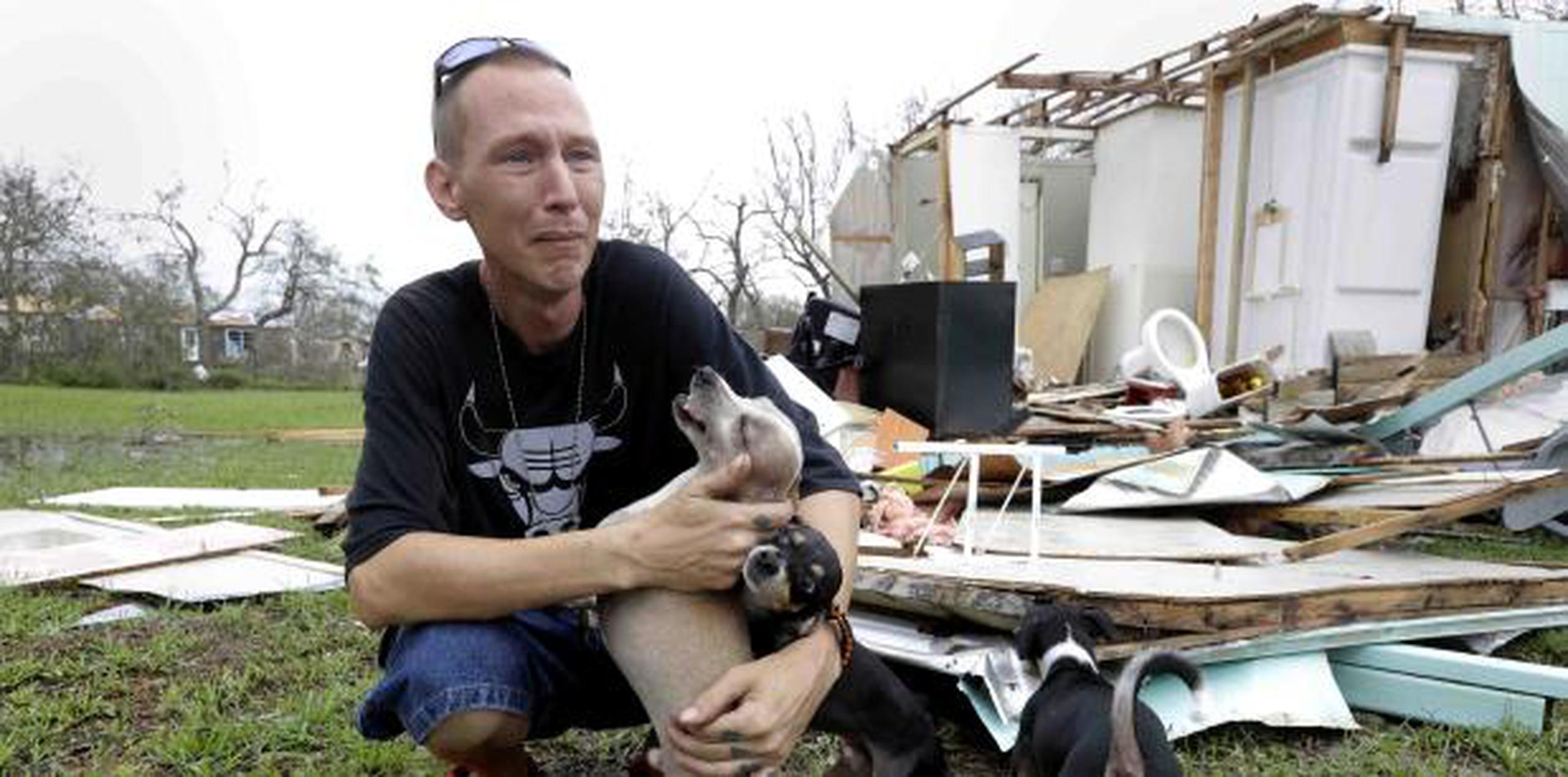 En esta foto del 27 de agosto de 2017, Sam Speights trata de contener las lágrimas mientras sostiene a sus perros y examina el daño a su casa a raíz del huracán Harvey en Rockport, Texas. (AP)