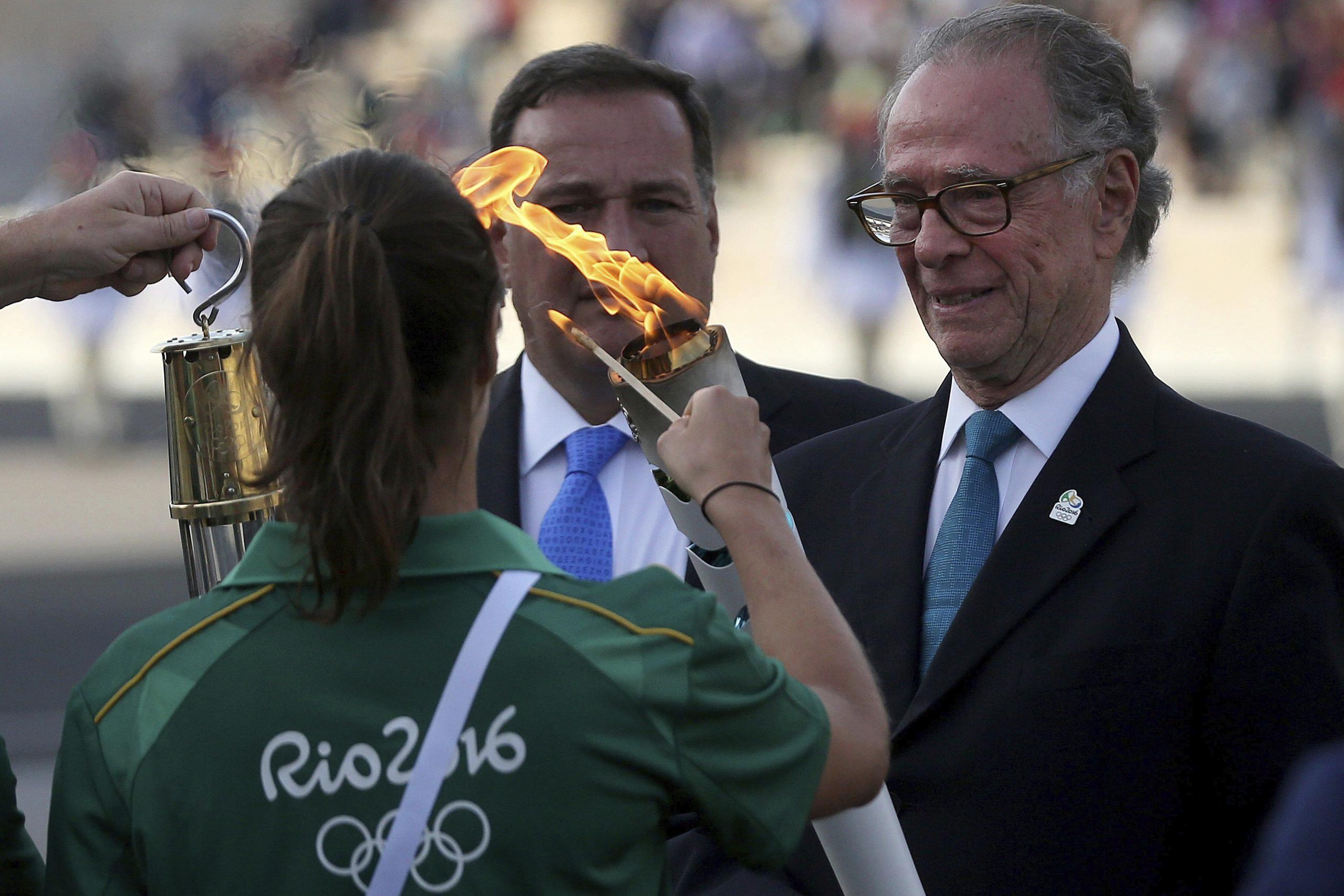 El presidente del Comité Olímpico griego, Spiros Kapralos (i) entrega la antorcha olímpica al presidente del Comité Organizador de Río 2016, Carlos Arthur Nuzman (d), durante la ceremonia de entrega en el estadio Panathinaiko, en Atena, Grecia. (EFE)