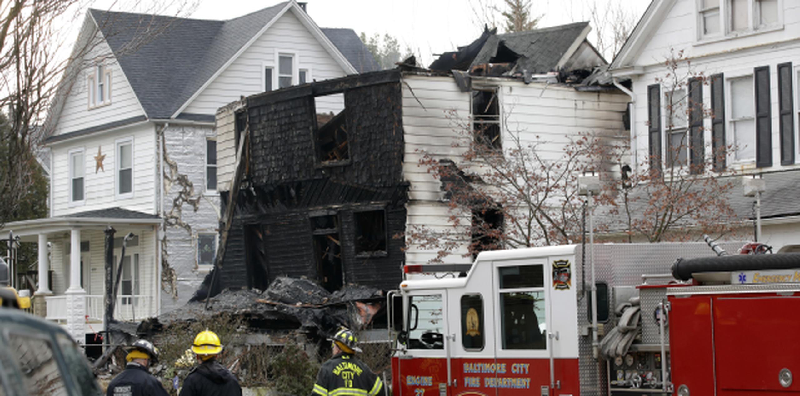 Funcionarios de los bomberos aparecen afuera de una casa que se quemó la mañana del jueves. (Prensa Asociada)