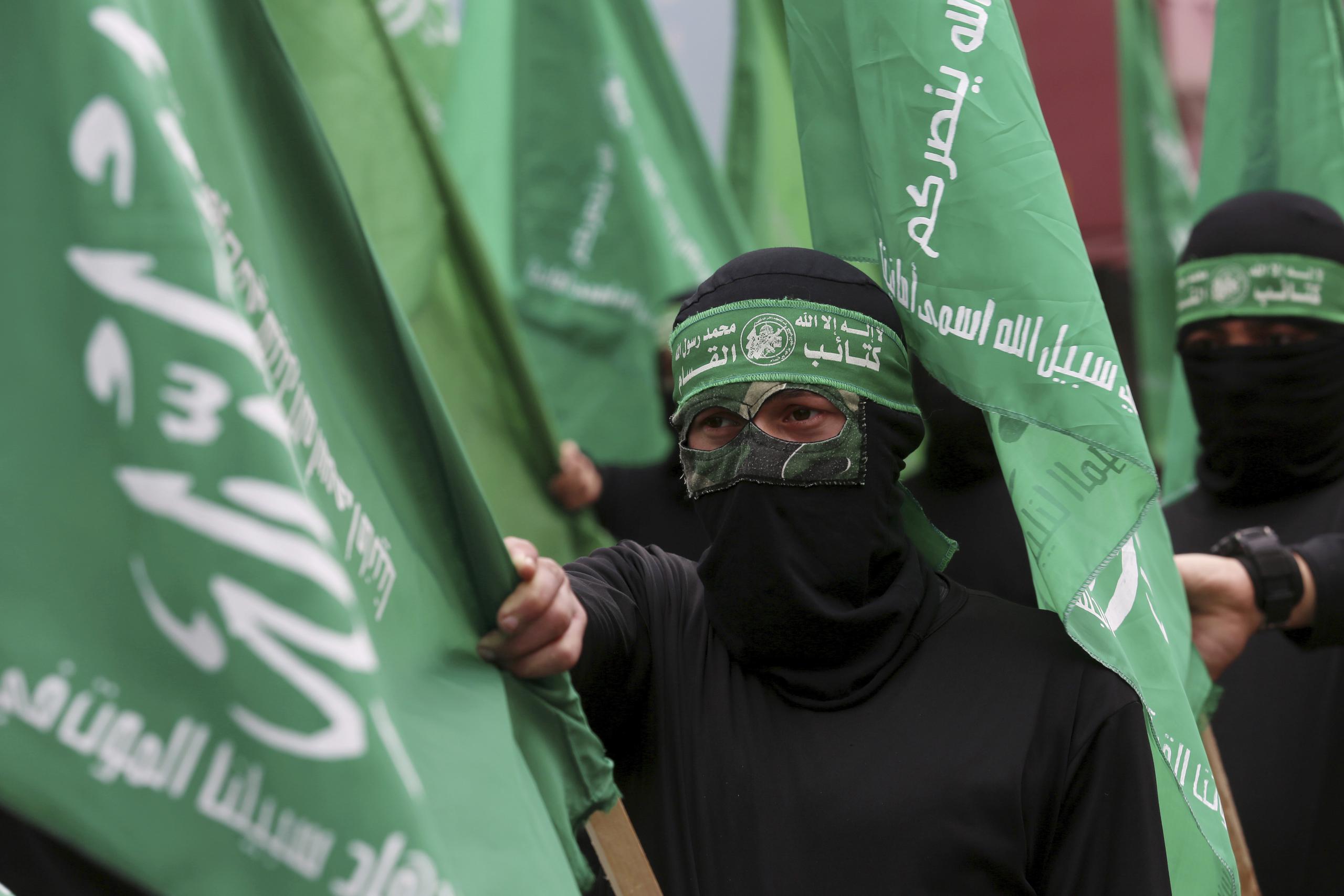 Milicianos encapuchados de Hamas ondean sus banderas verdes en una protesta en la calle principal de Ciudad de Gaza. (AP/Adel Hana)