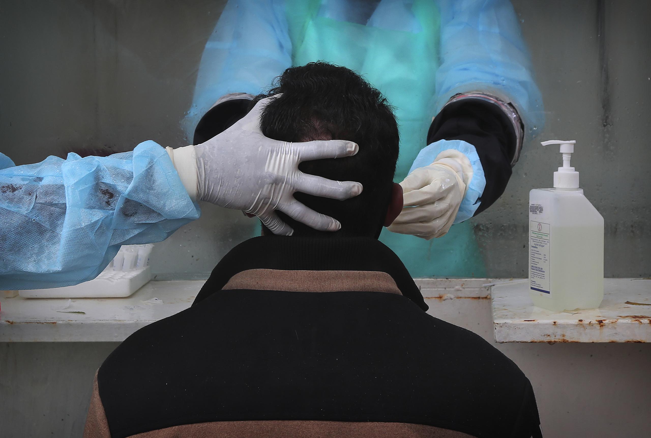 Personal médico extrae una muestra nasal a una persona para una prueba de detección del coronavirus en un hospital gubernamental en Hyderabad, India