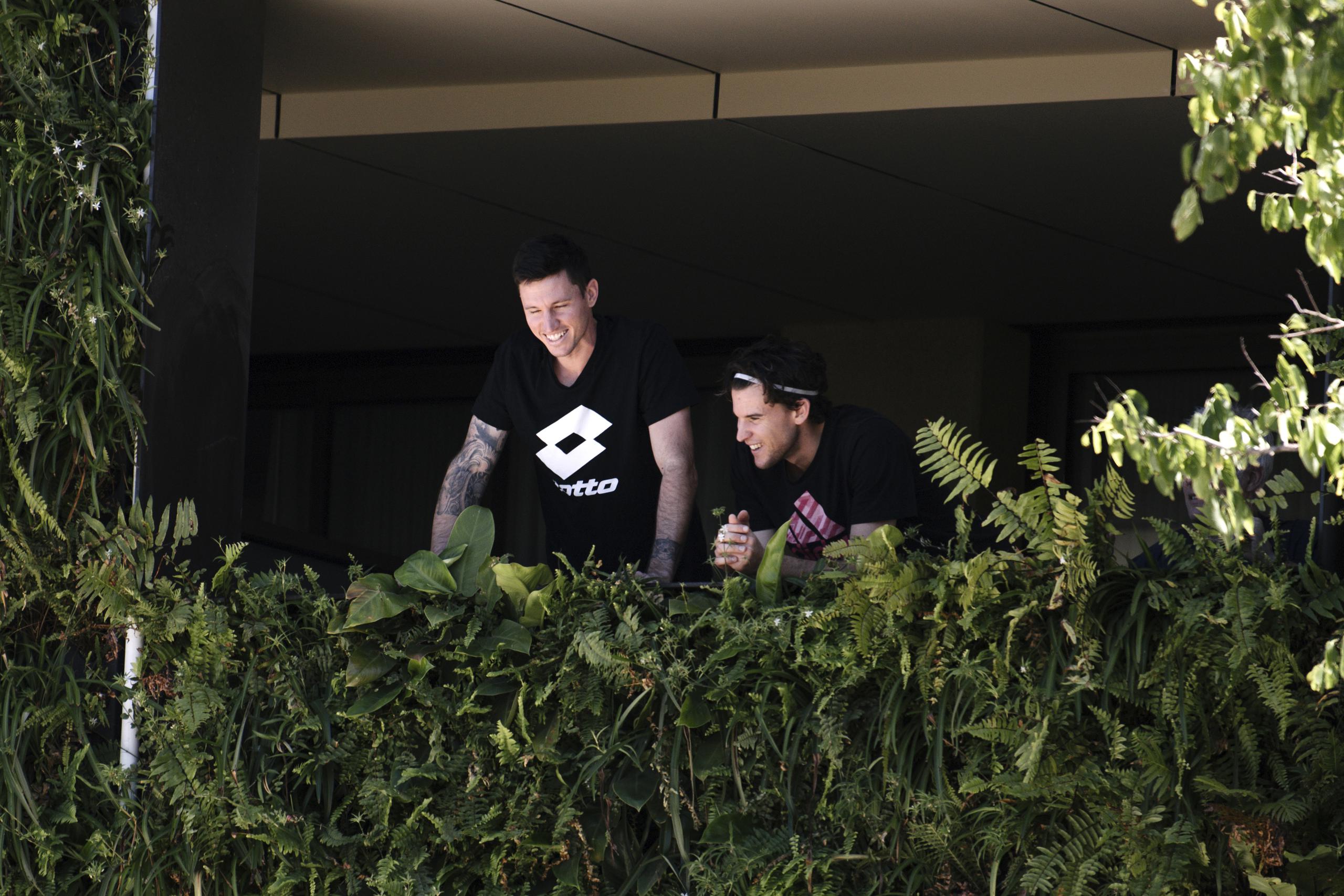El tenista local australiano Dominic Thiem (derecha), aparece acompañado por un hombre no identificado en el balcón de su residencia en Adelaida, Australia, el martes 19 de enero de 2021.