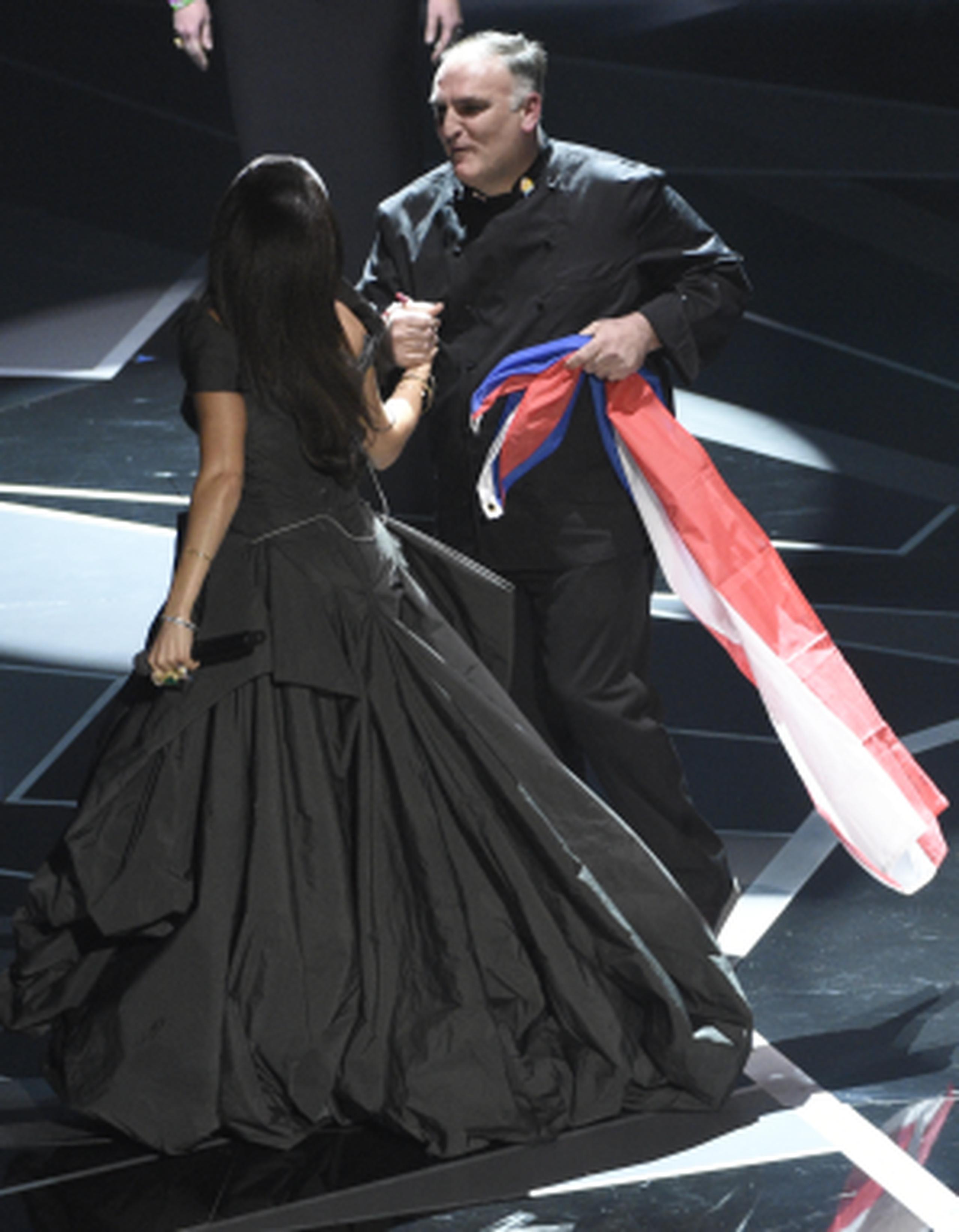 La cantante Andra Day saluda al chef José Andrés, quien lleva en su mano una bandera de Puerto Rico. (AP)
