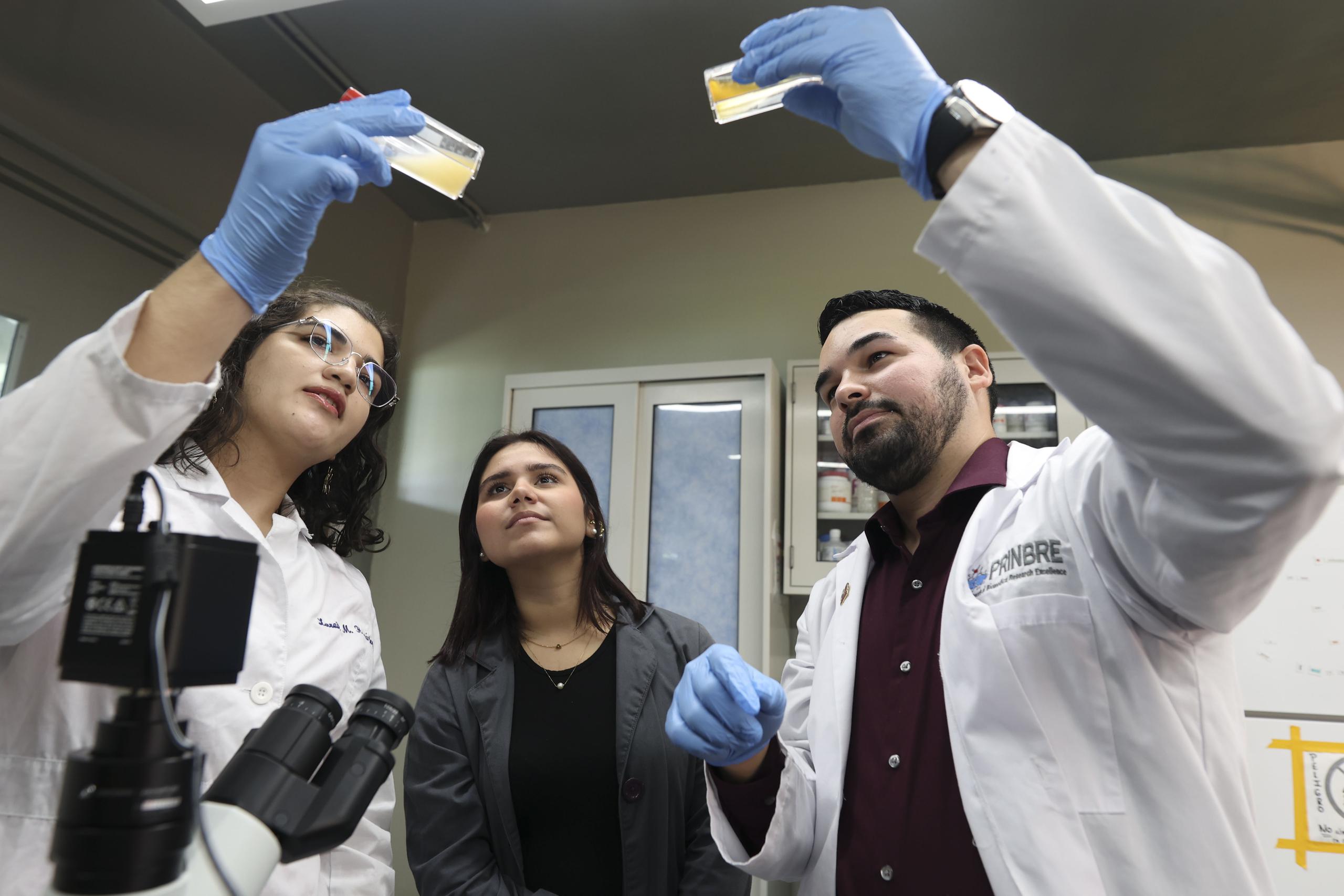 Desde la izquierda, las estudiantes Lorraine Hernández Delgado y Gabriela Paz Alvira, junto al profesor del Departamento de Biología, Kevin Alicea Torres. El grupo trabaja una investigación sobre inmunoterapias para combatir el cáncer.