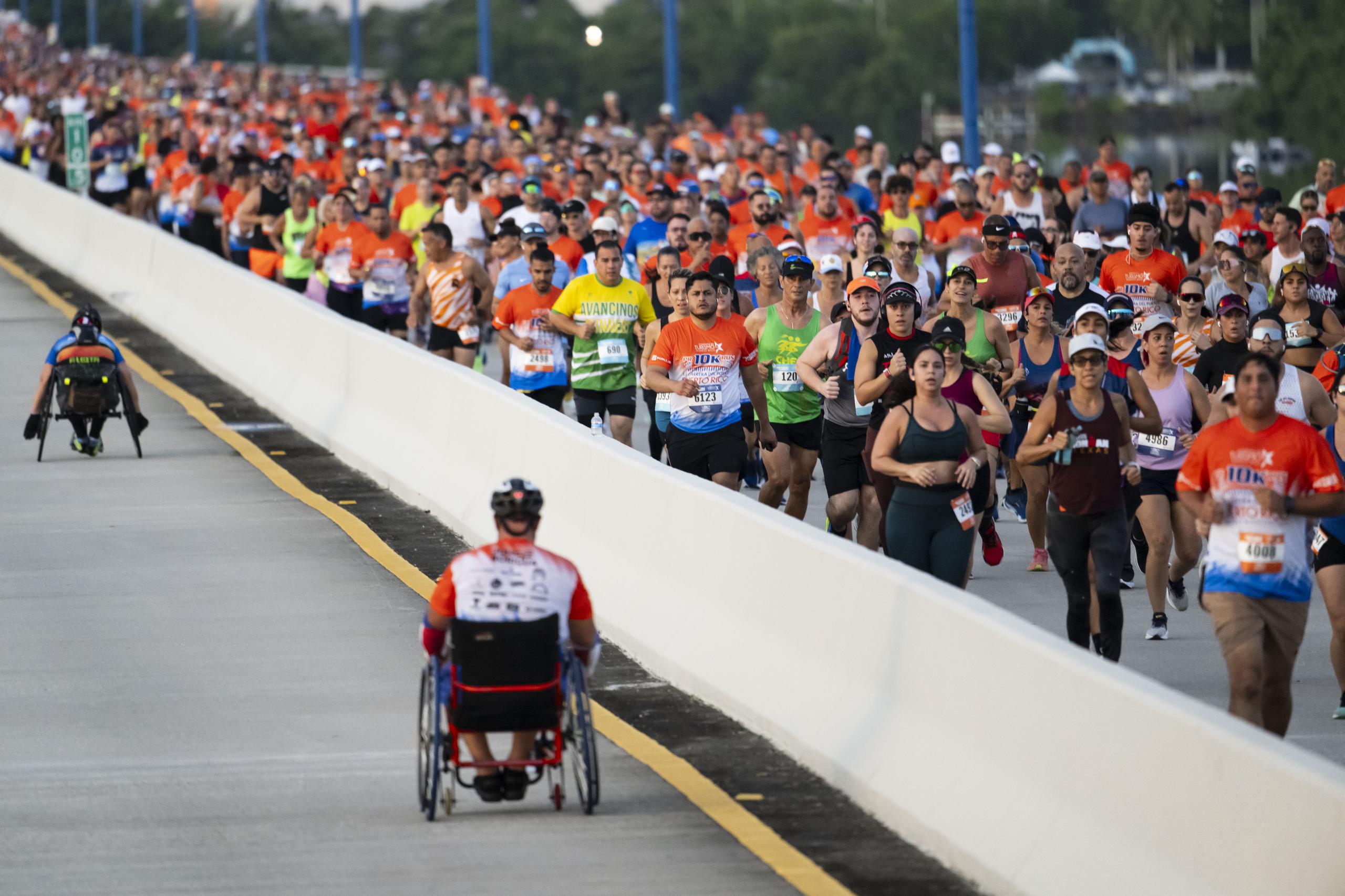 Cientos de miles de corredores hacen su parte y apoyan a la clase de silla de rueda durante el trayecto sobre el puente Teodoro Moscoso.