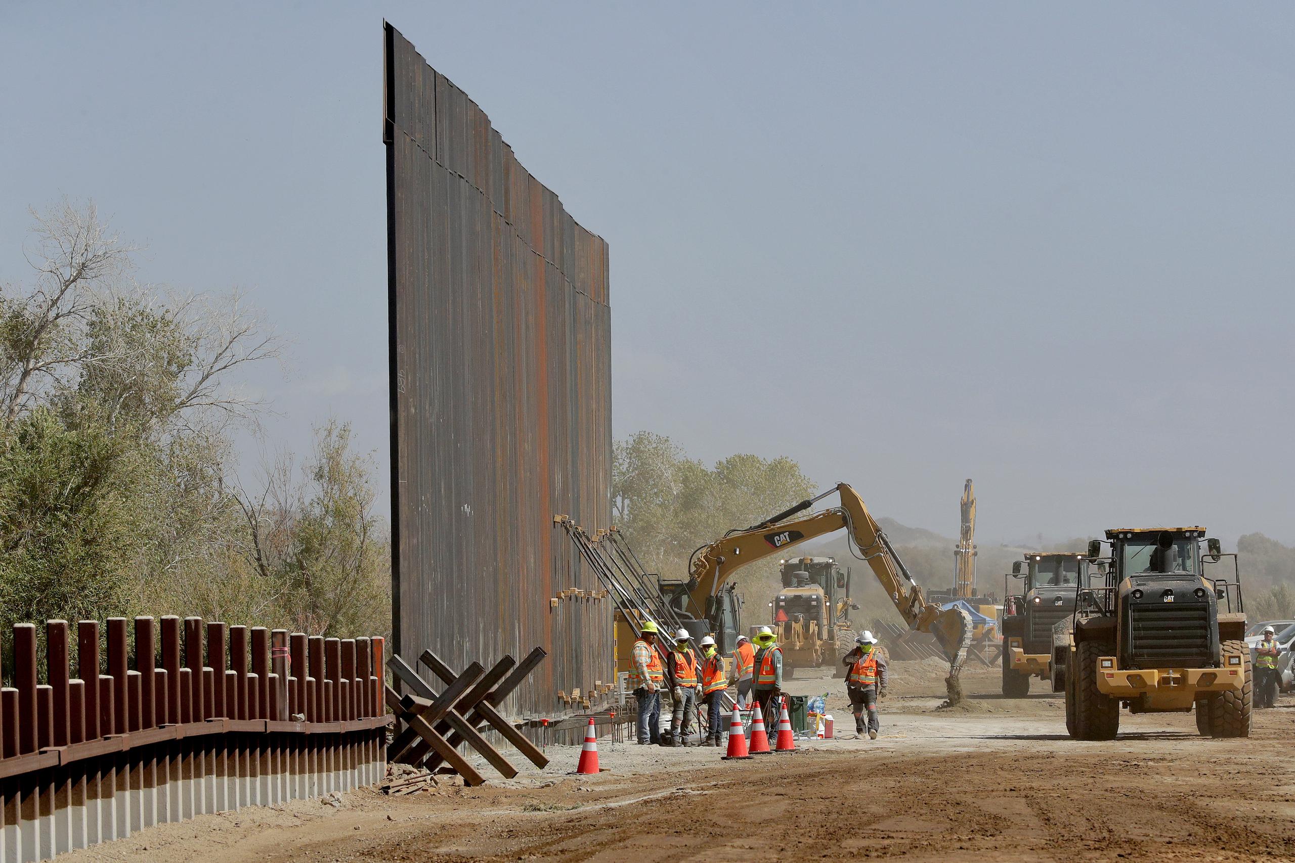 Trabajadores de contratistas del gobierno erigen una sección del muro fronterizo financiado por el Pentágono a lo largo del río Colorado en Yuma, Arizona