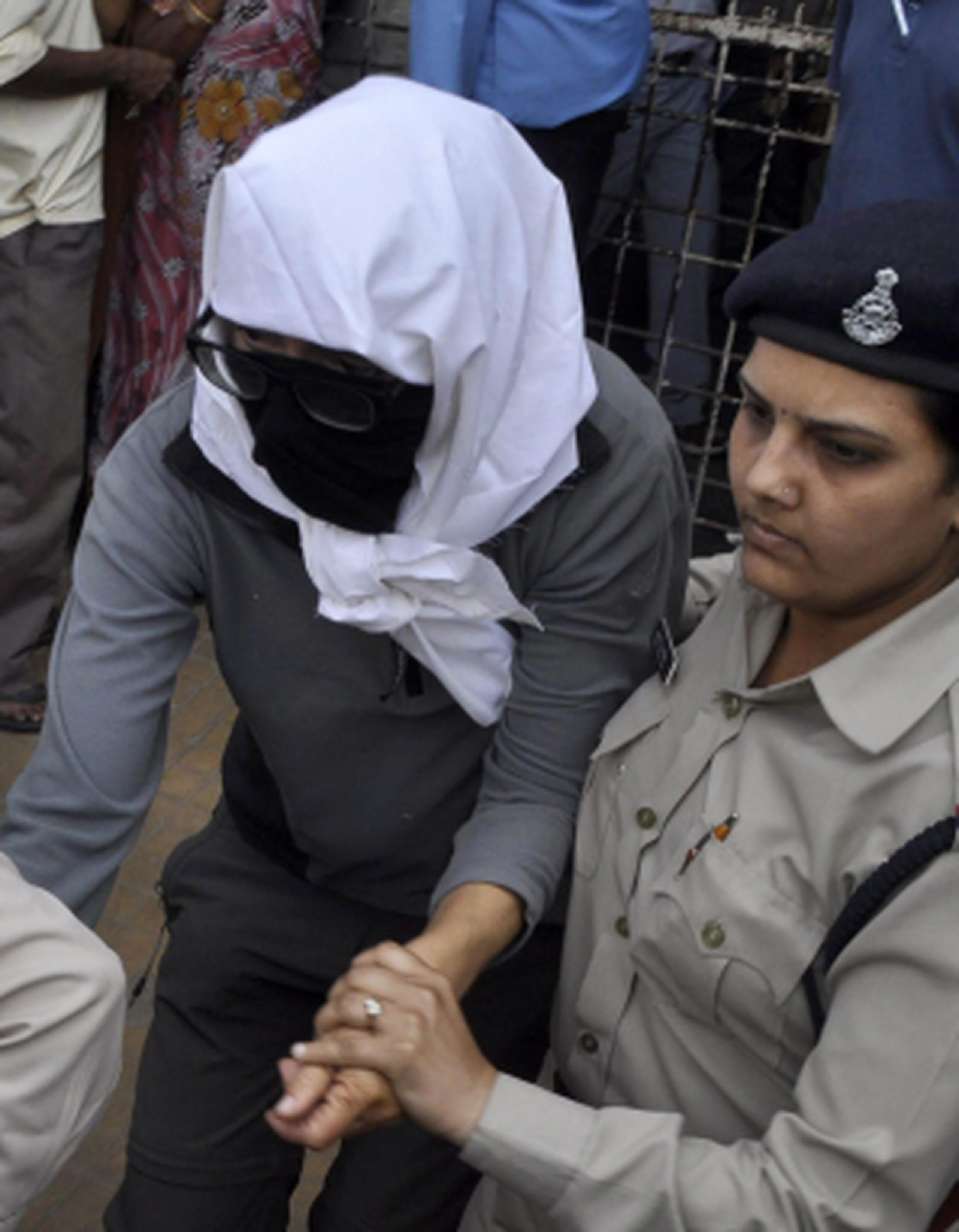 En una fotografía difundida en la prensa aparece la mujer con una capucha que le cubre el rostro al momento que la policía la escolta al hospital. (EFE)