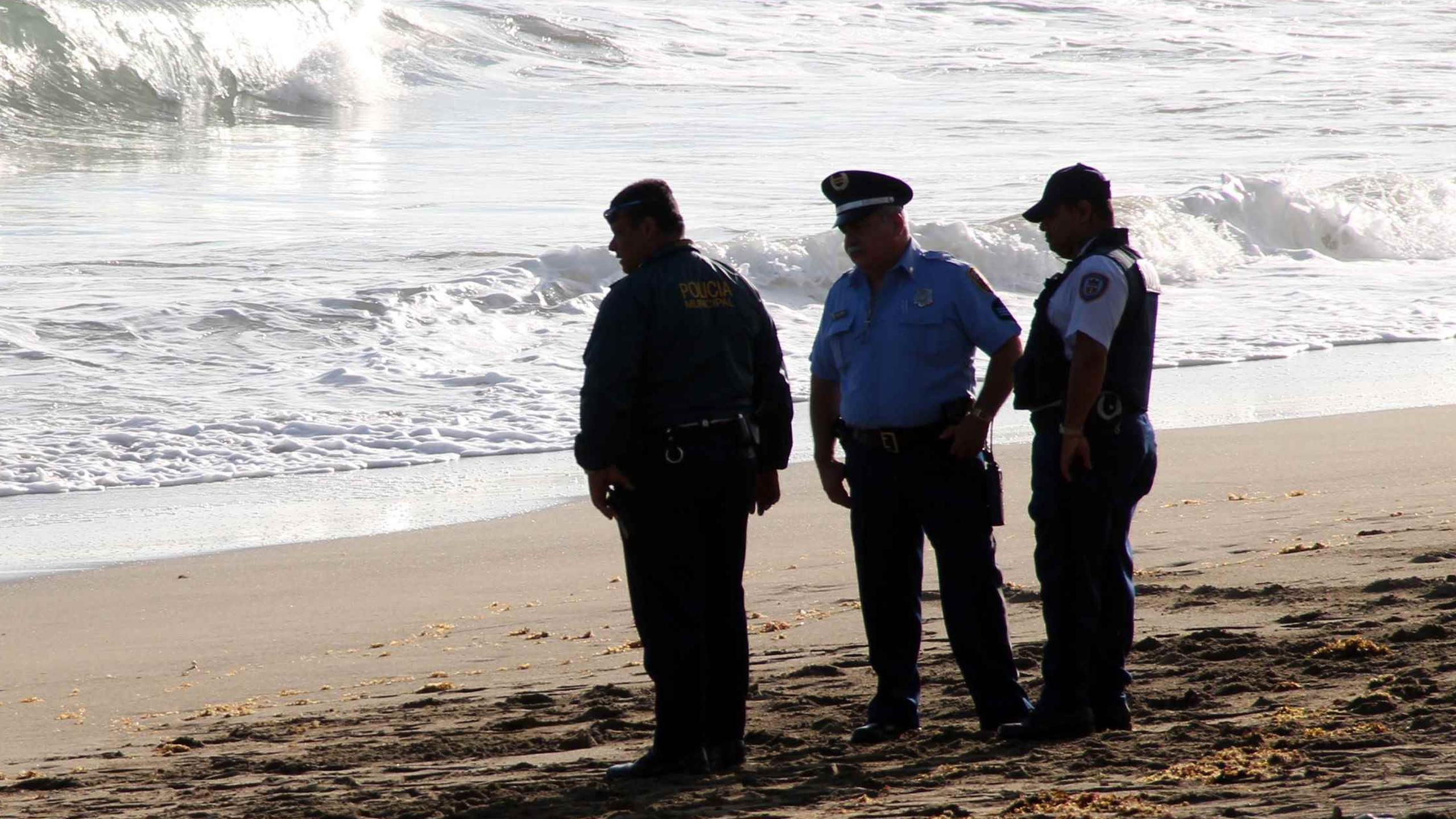 Tres agentes de la Policía investigan un ahogamiento en la playa. (GFR Media)