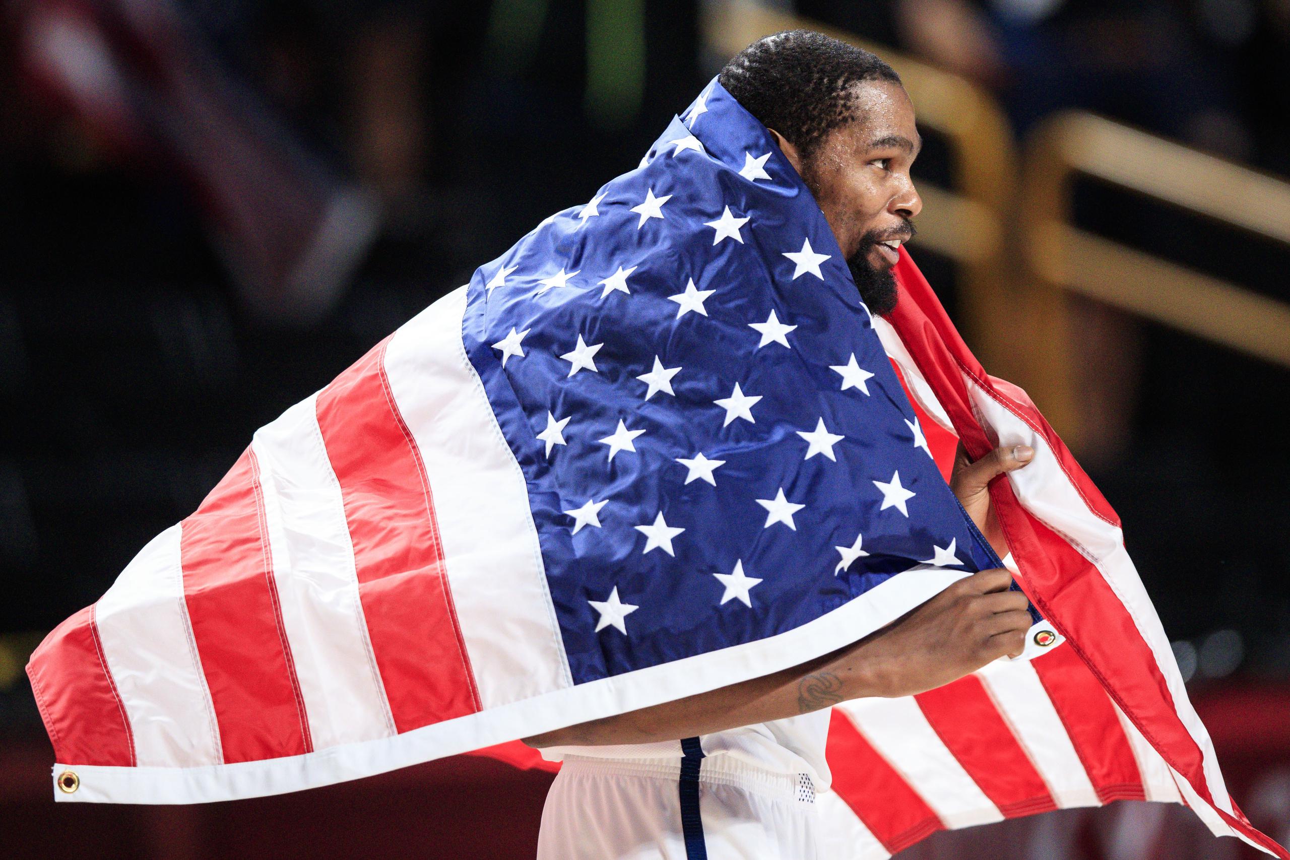El canastero estadounidense Kevin Durant se arropa con la bandera luego de que Estados Unidos ganara la medalla de oro en el baloncesto masculino de Tokio 2020 al derrotar a Francia.
