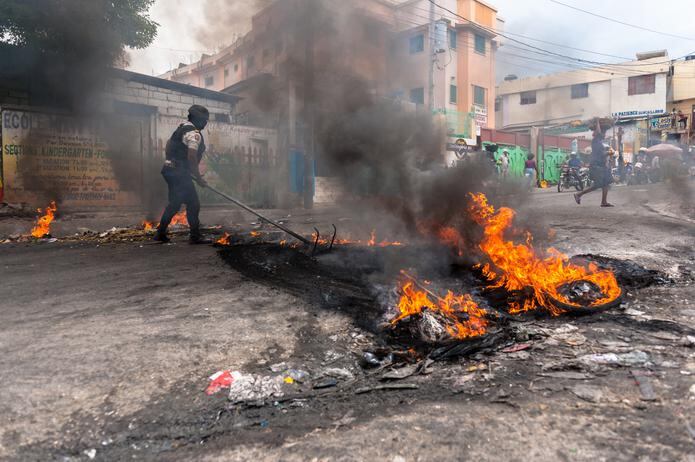 Un policía intenta disipar una barricada en llamas durante una jornada de protesta, el 6 de enero de 2022, en Pétion-ville (Haití). EFE/ Johnson Sabin
