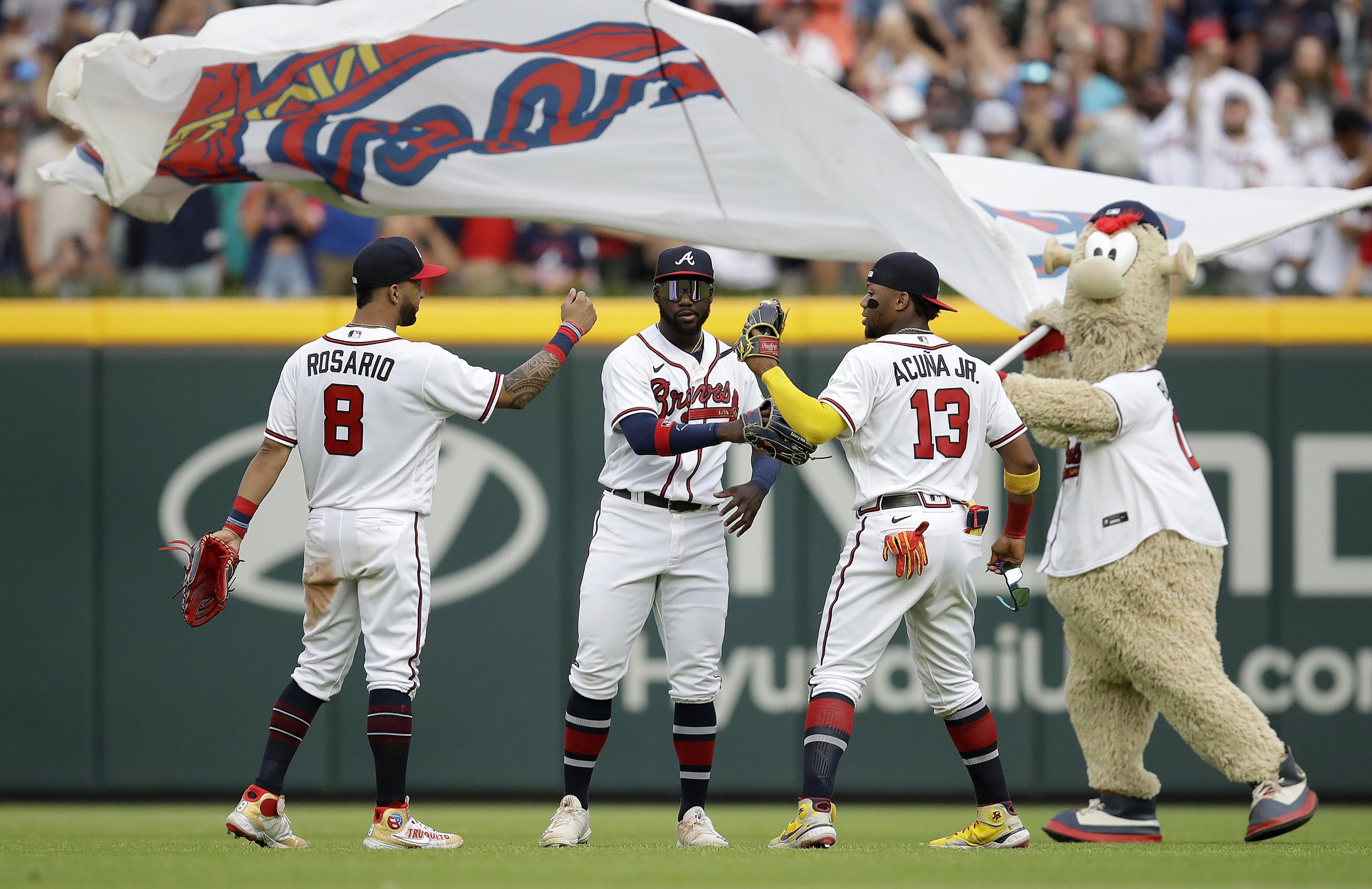 Eddie Rosario celebra con Guillermo Heredia, Ronald Acuna Jr. y la mascota Blooper después de que los Braves vencieran a los Nationals.