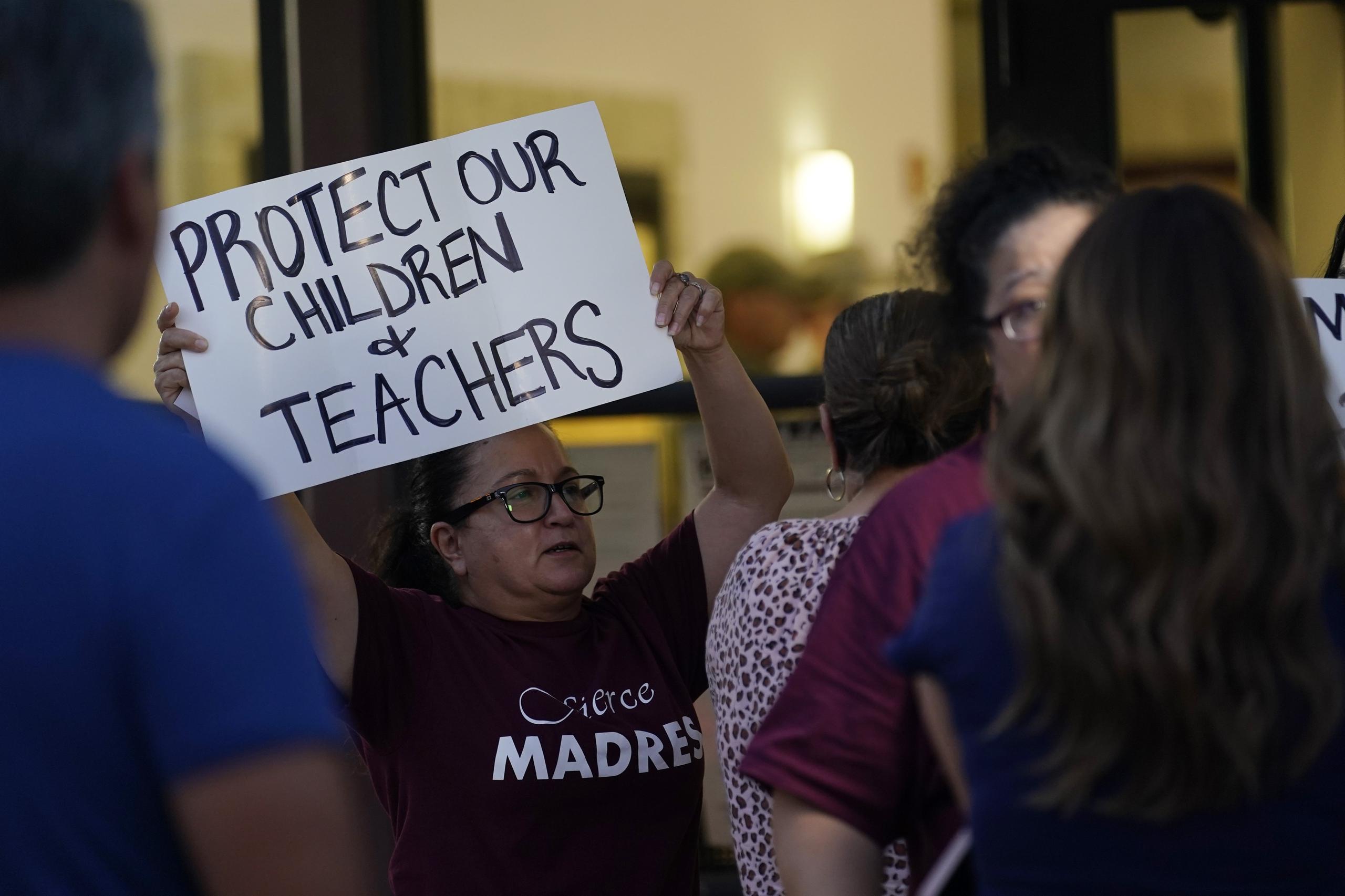 Padres y familiares de estudiantes sostienen carteles de protesta durante una reunión especial de la Junta Directiva del Distrito Escolar Independiente Consolidado de Uvalde donde los padres abordaron los tiroteos en la Escuela Primaria Robb, el lunes 18 de julio de 2022, en Uvalde, Texas. (Foto AP/Eric Gay)