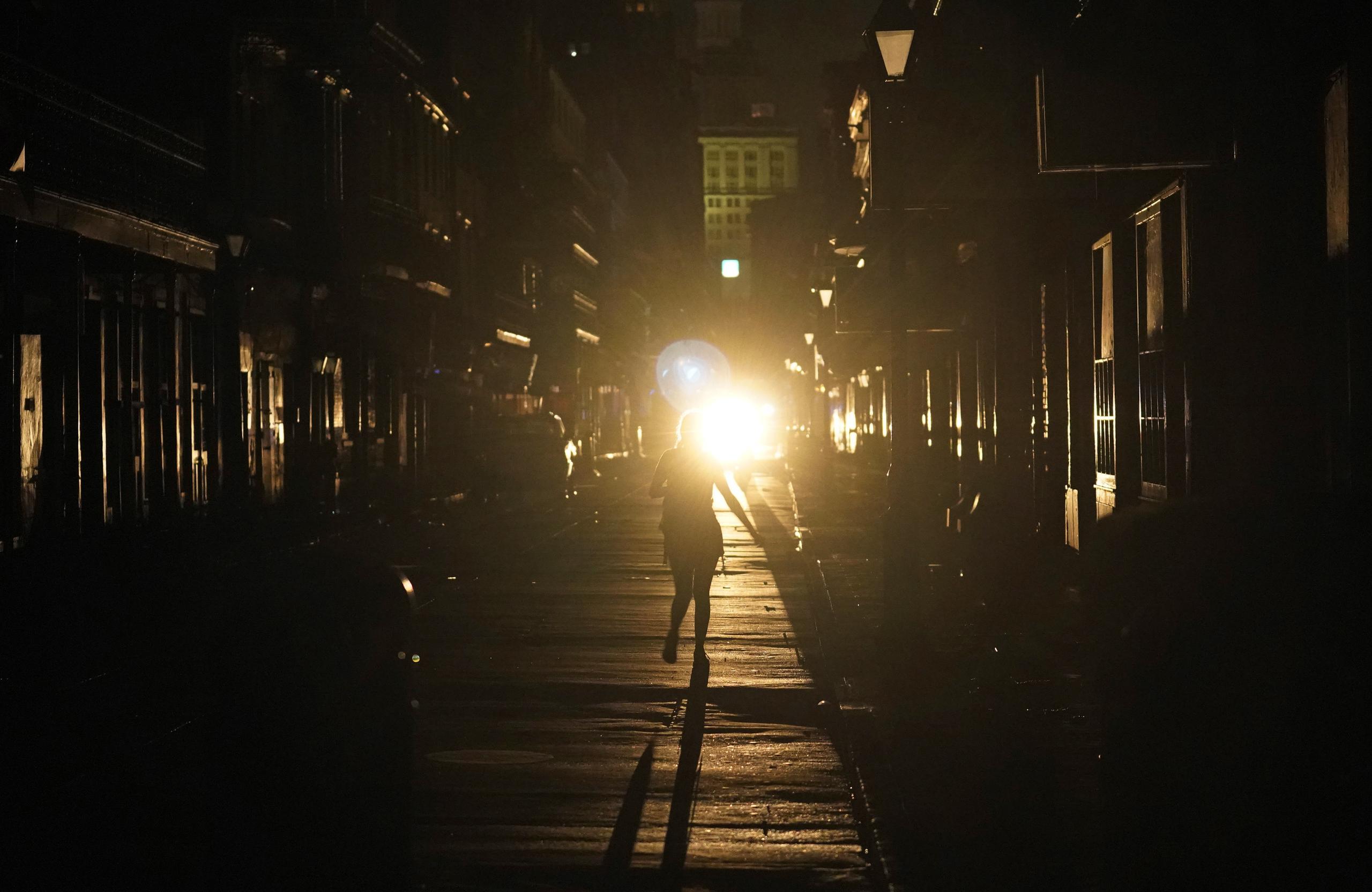 Un policía patrulla junto a una mujer que camina en una calle de Nueva Orleans, luego de que la ciudad se quedó sin luz tras el paso del huracán Ida. (AP Foto/Eric Gay)
