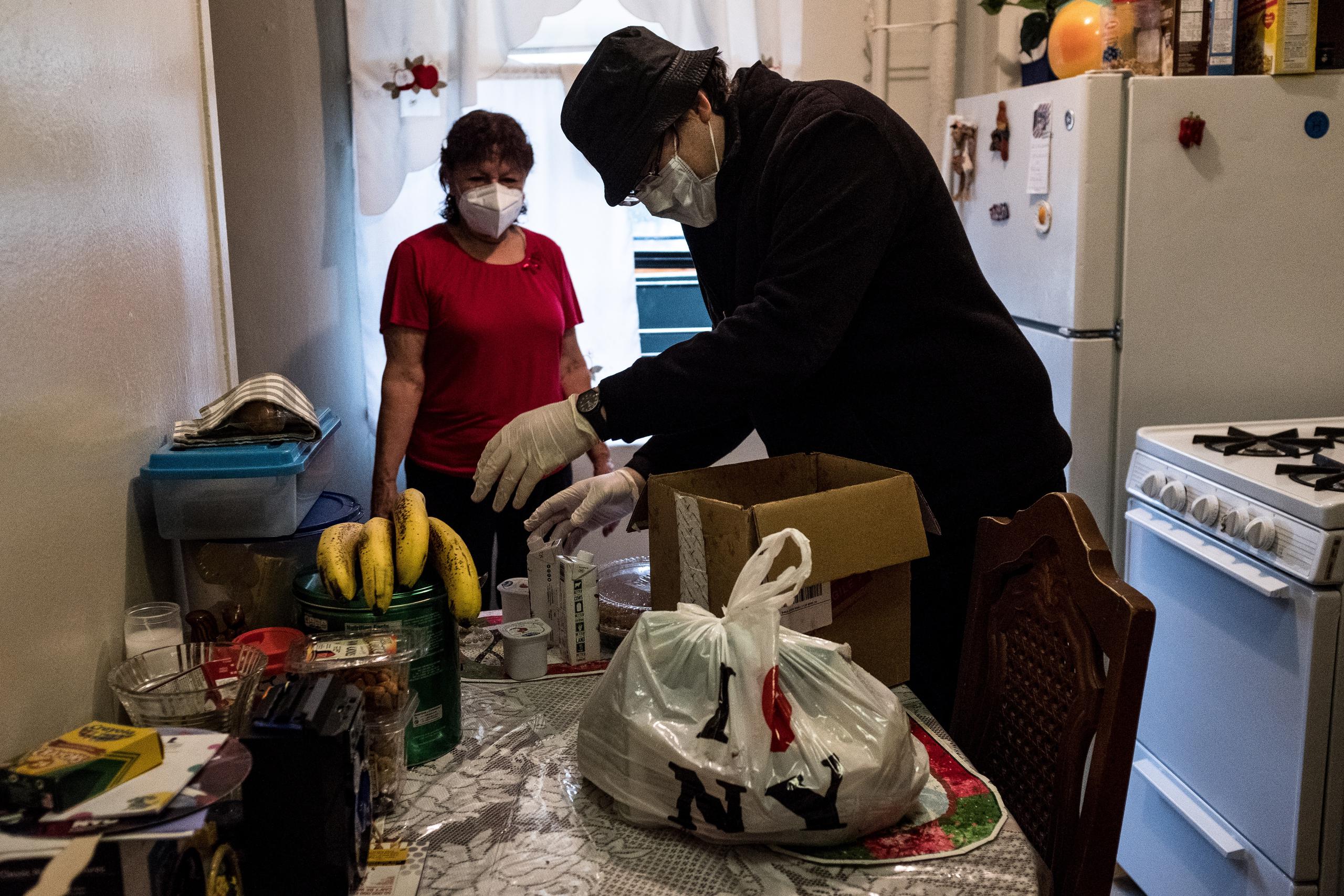 El padre Pedro González hace una entrega de comida a Gloria, una feligrés de 75 años originaria de El Salvador, que debido a su edad no sale de su casa en el Bronx, Nueva York