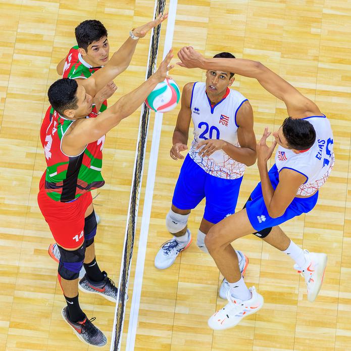 Antonio Elías de la Selección Nacional de Voleibol de Puerto Rico intenta un remate ante dos defensores de México. (Norceca)