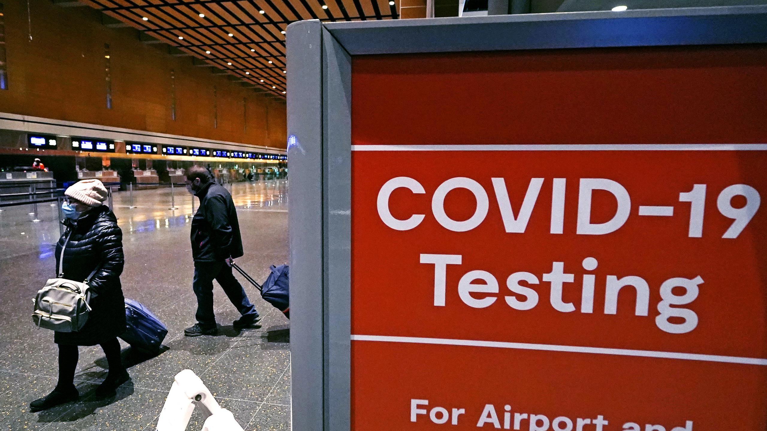 Viajeros pasan junto a un letrero cerca de un centro de pruebas de COVID-19 en la Terminal E del aeropuerto Logan el 21 de diciembre de 2021, en Boston. (AP Foto/Charles Krupa, Archivo)