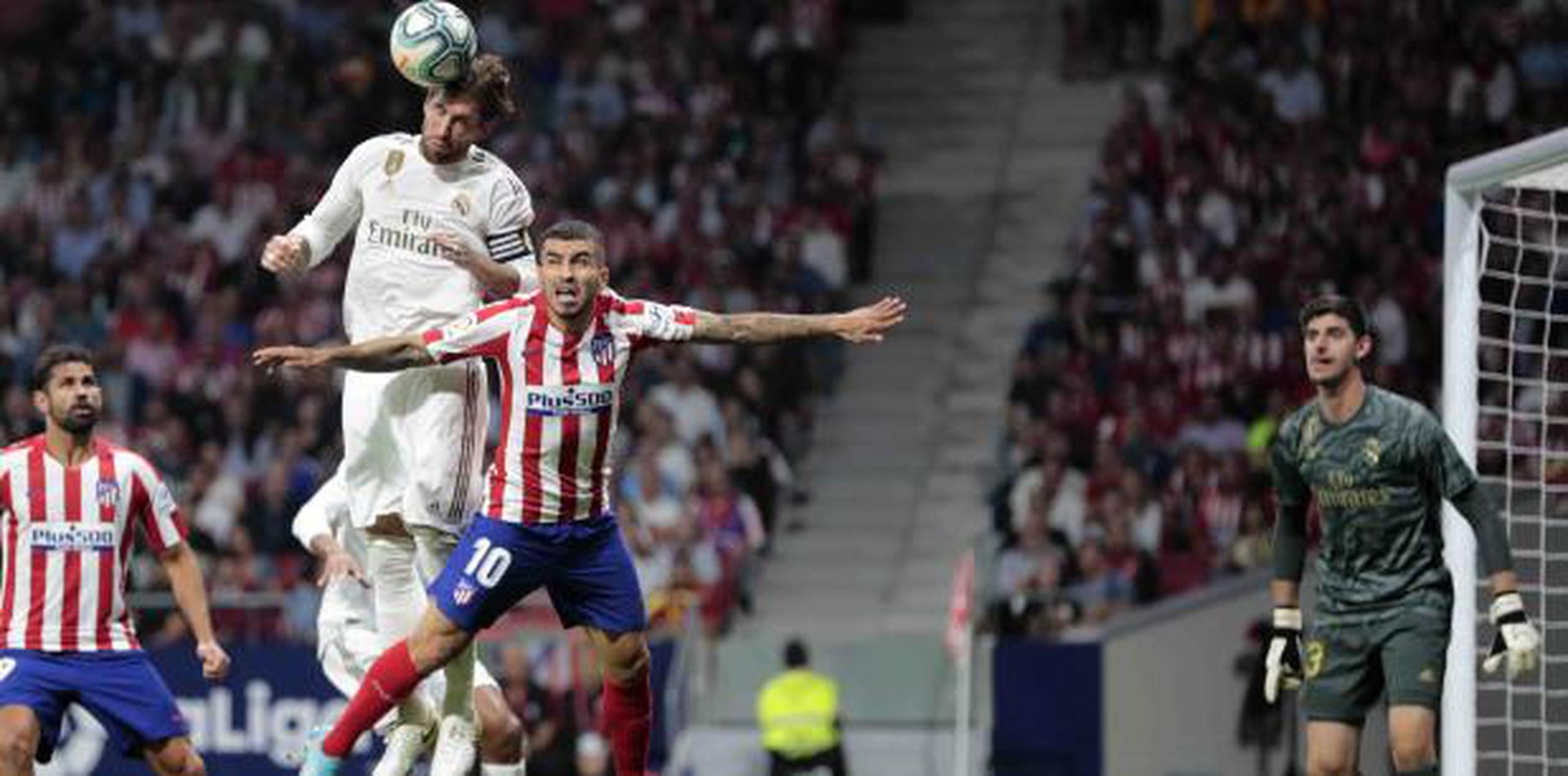 Sergio Ramos, del Real Madrid, cabecea el balón para evitar un intento de gol del Atlético de Madrid. (AP)