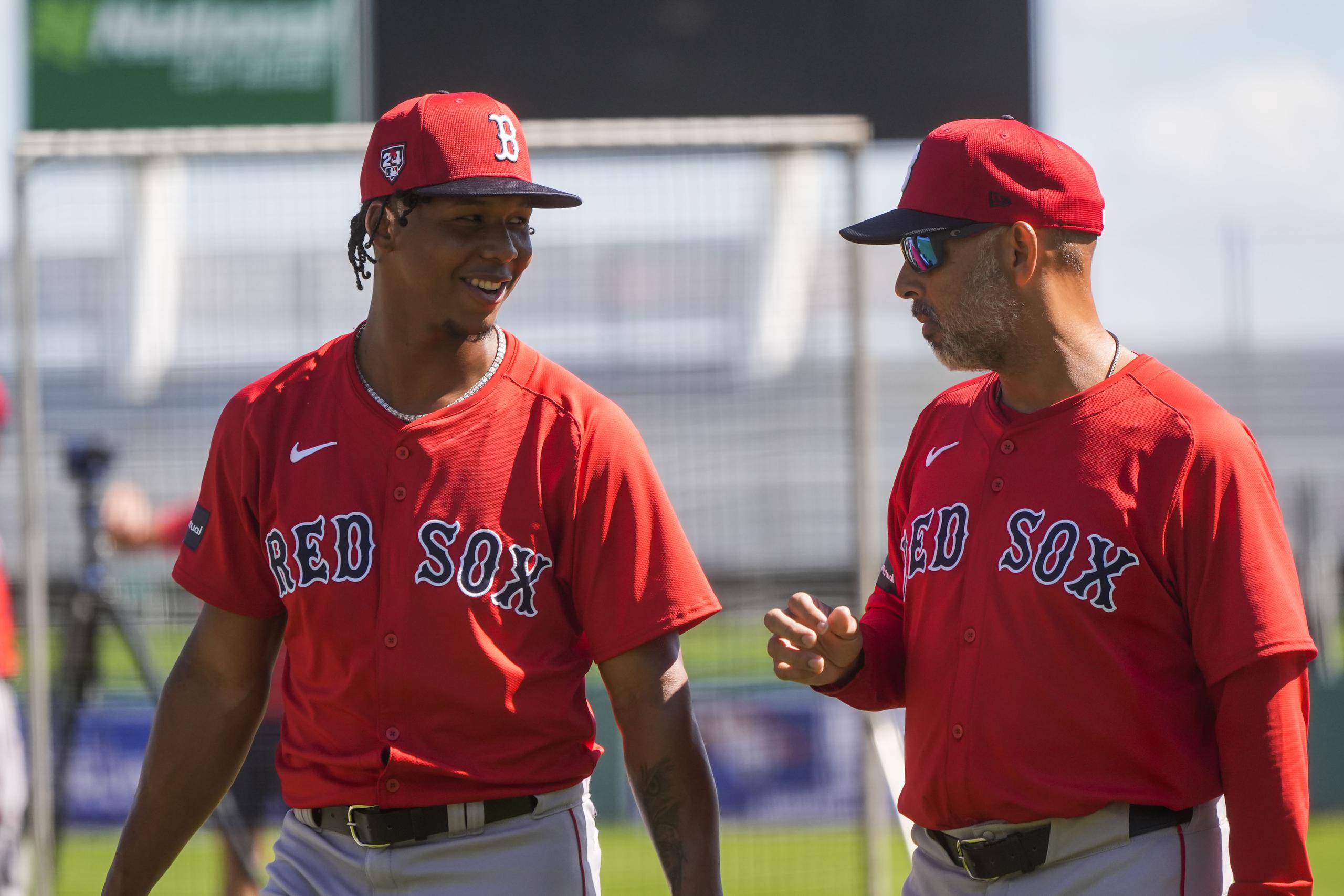 El lanzador dominicano Brayan Bello, a la izquierda, conversa con el mánager Alex Cora. Bello pudiera ser uno de los principales brazos de los Red Sox en la temporada, pese a su corta experiencia.