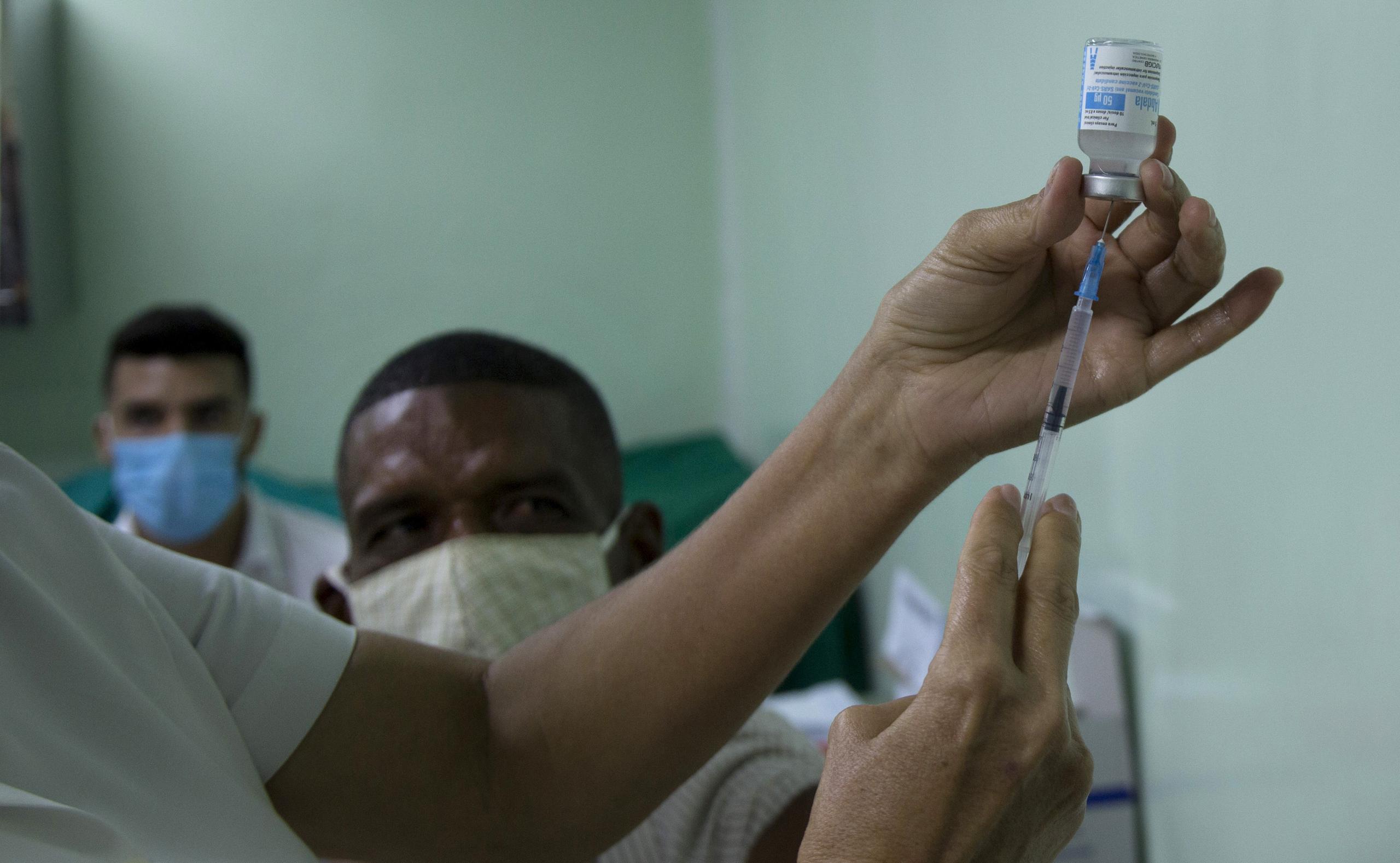 Eusebio Torres espera ser vacunado mientras una enfermera prepara la dosis de la vacuna cubana Abdala para el COVID-19 en el hospital Gustavo Aldereguia de Cienfuegos, Cuba.