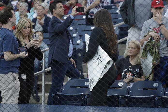 Una empleada del estadio se lleva el cartel de un aficionado previo al juego de pretemporada entre los Astros de Houston y los Nacionales de Washington.