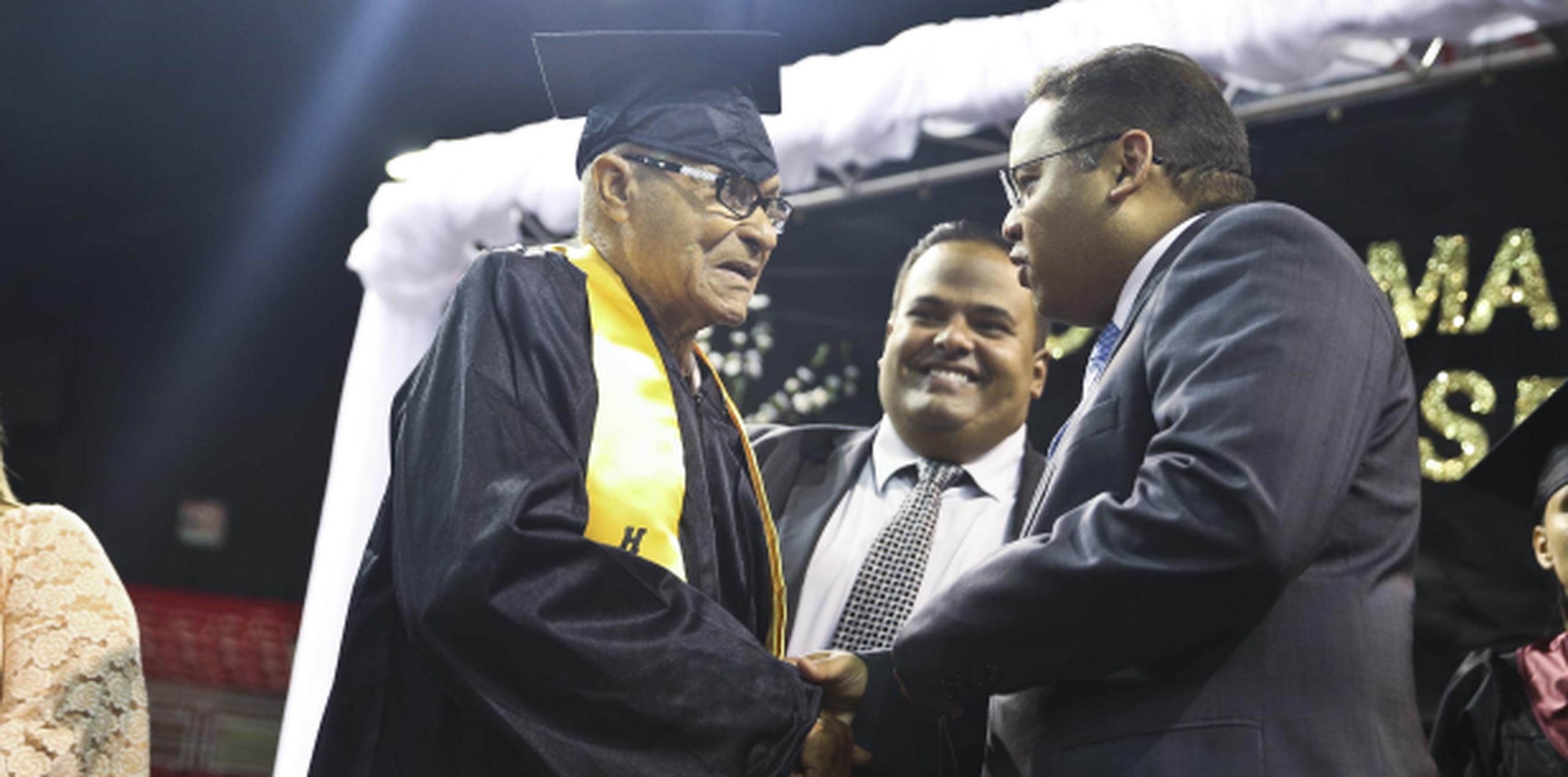 El recién graduado Elías Rivera, de 85 años, estrecha la mano del secretario de Edcación Rafael Román. (wandaliz.vega@gfrmedia.com)