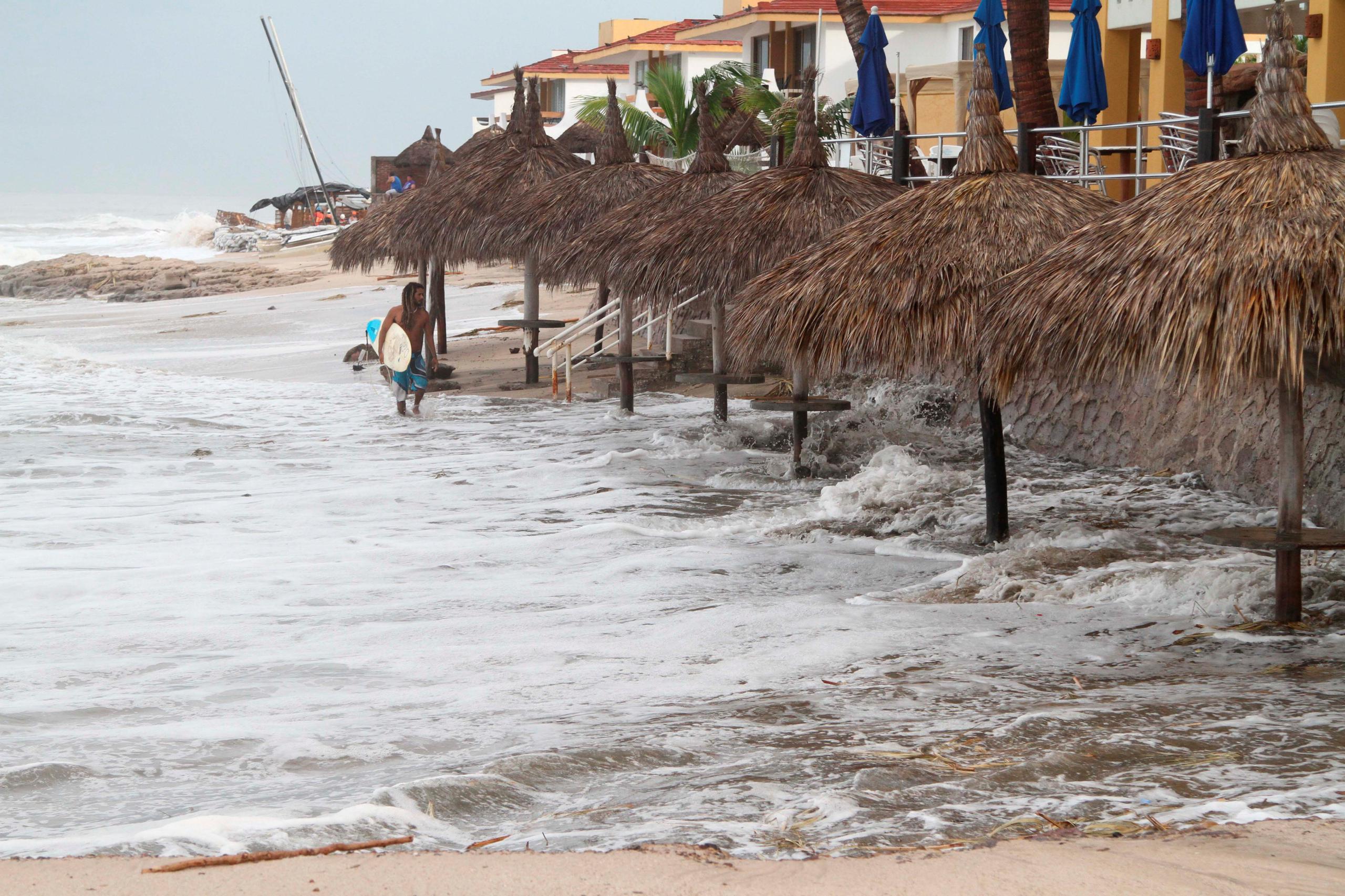 Fotografía de archivo en la que se observa a un hombre caminando en una playa frente a grandes olas el puerto de Mazatlán del estado mexicano de Sinaloa. EFE
