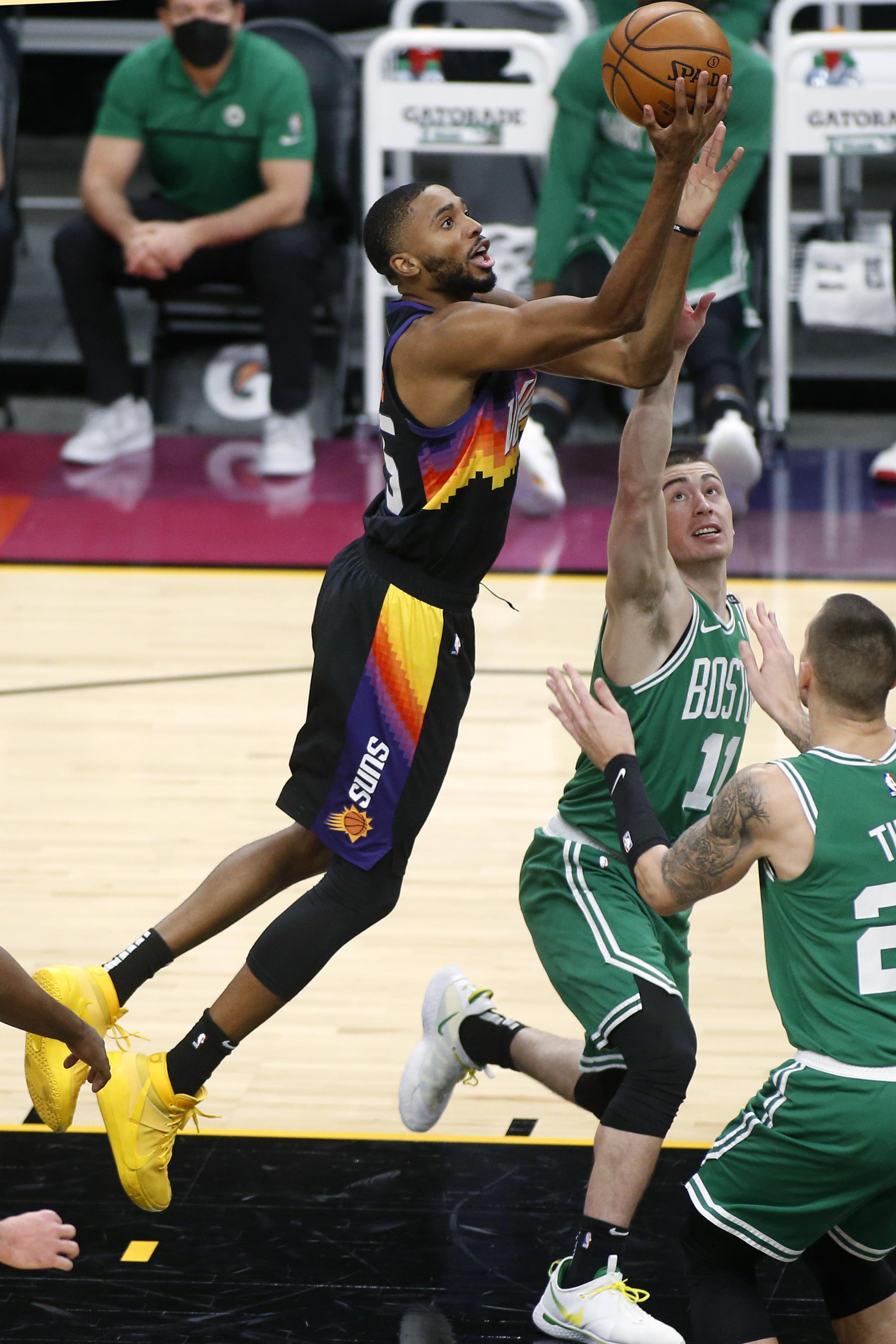El alero de los Suns de Phoenix Mikal Bridges lanza el balón mientras lo defienden Payton Pritchard y Daniel Theis de los Celtics de Boston.