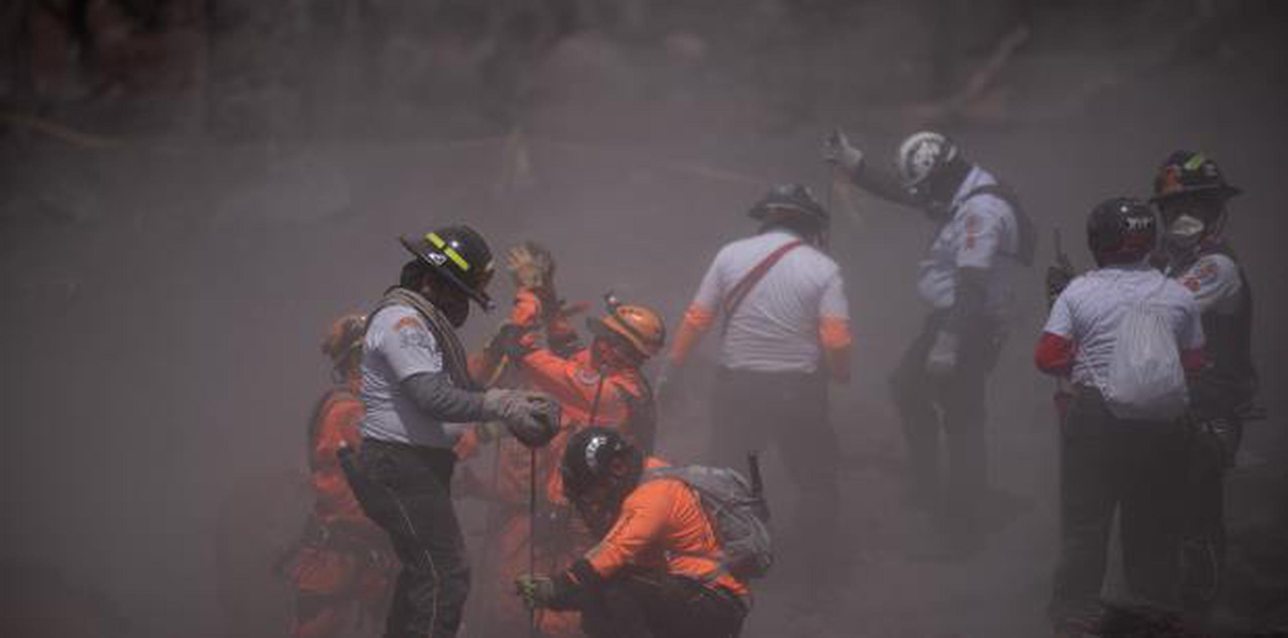 Los trabajadores equipados con palas y equipamiento pesado encontraron más víctimas mortales de la erupción del domingo. (EFE/ Santiago Billy)