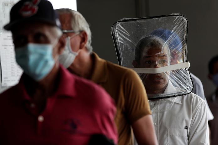 Zaul Ortega, de 53 años, se cubre el rostro con una bolsa plástico mientras hace fila para comprar en un supermercado, durante la pandemia del coronavirus, en Ciudad de Panamá