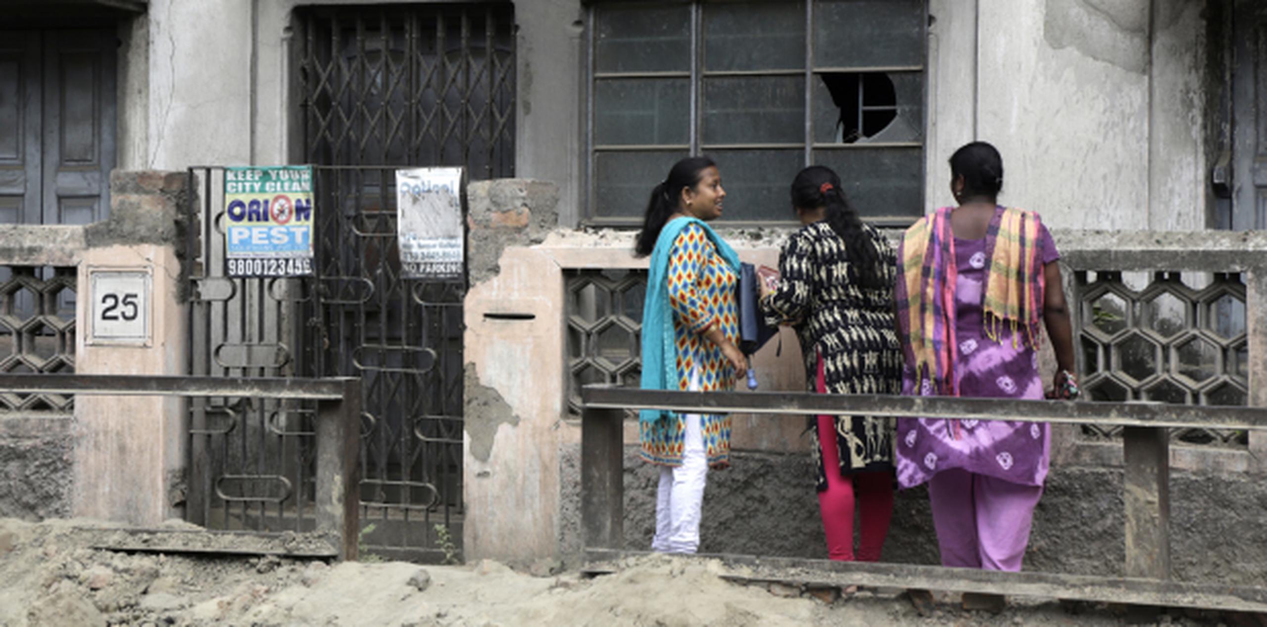 Curiosos intentan mirar por la ventana de donde Subhabrata Majumdar, preservó el cadáver de la madre Bina Majumdar durante tres años en Kolkata, India. (AP) (Archivo)
