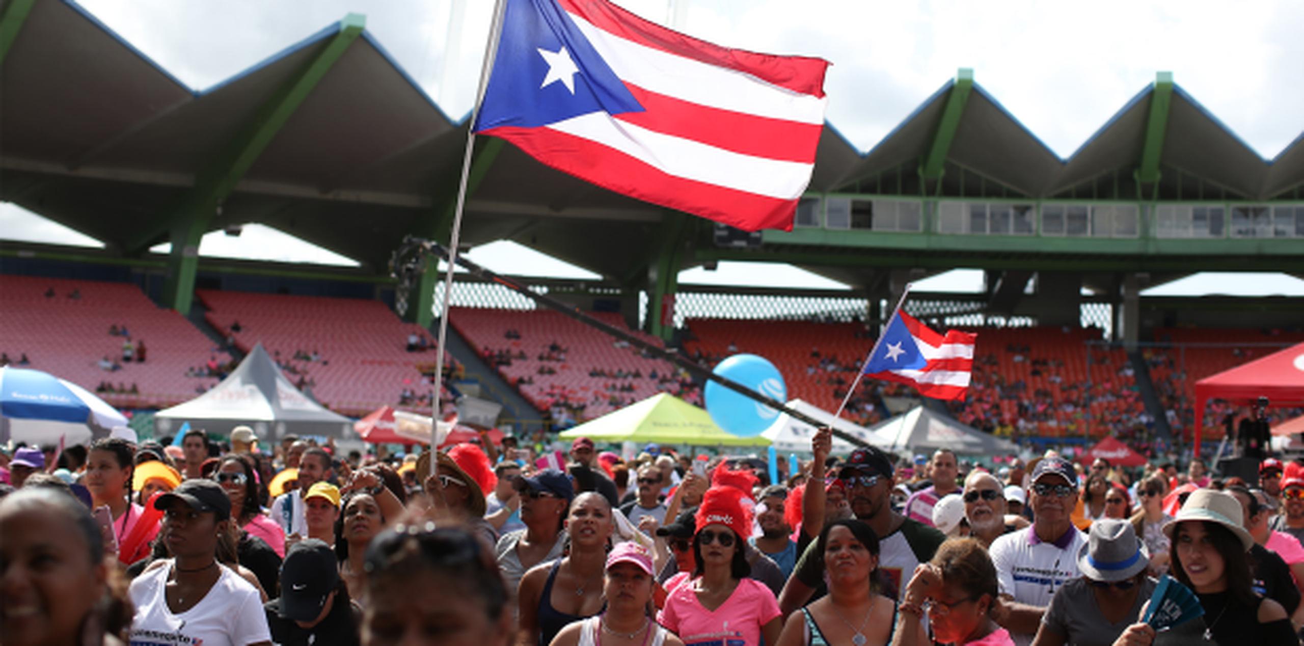 Para entonces cientos de personas habían llegado bajo el sol inclemente dispuestos a darse su bailadita y cantar, algunos ondeando banderas de Puerto Rico. (Fotos / José Cruz Candelaria)