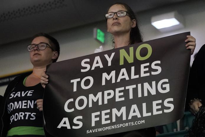 Estas damas sostienen una pancarta que reclama se prohíba la participación de atletas trans en el deporte femenino mientras Lia Thomas competía en el campeonato nacional de natación de la NCAA. La joven Thomas, una nadadora trans, compitió entre el 2017 y 2019 para el equipo masculino de Penn State.