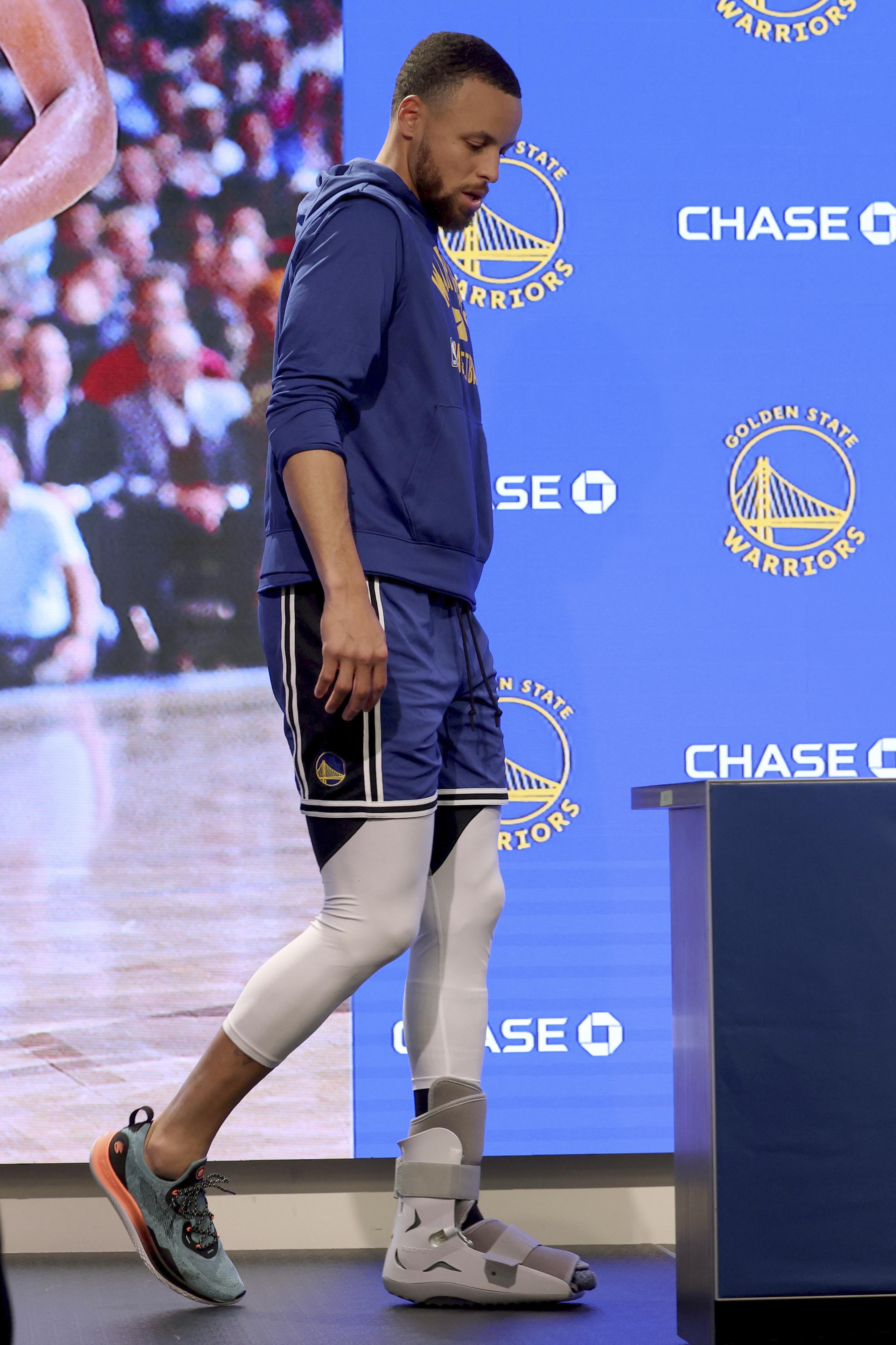 Curry utilizó una bota protectora blanca en el pie el domingo al conversar con los reporteros .