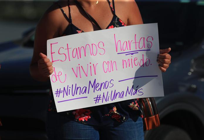 Una mujer sostiene una pancarta que lee: "Estamos hartas de vivir con miedo".
