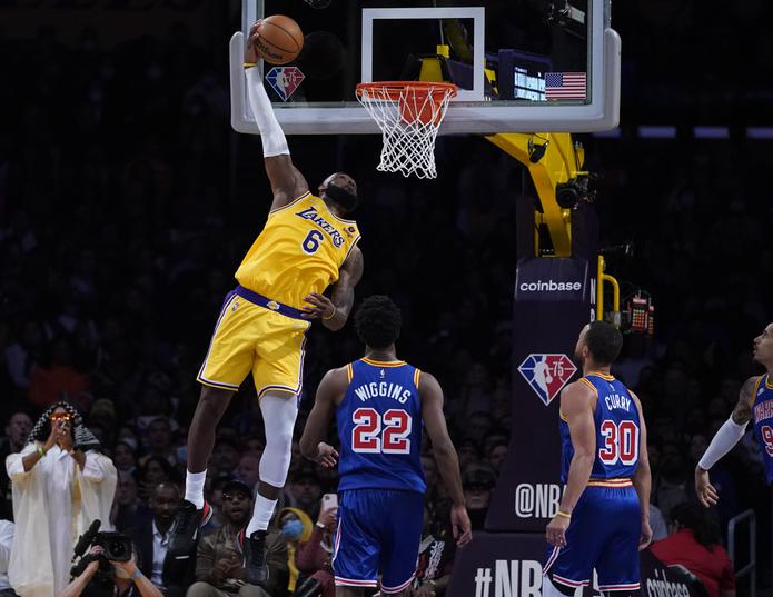 LeBron James, de los Lakers de Los Angeles, donquea un balón durante la segunda mitad del encuentro del sábado ante los Warriors de Golden State. Observan Andrew Wiggins (22) y Stephen Curry.
