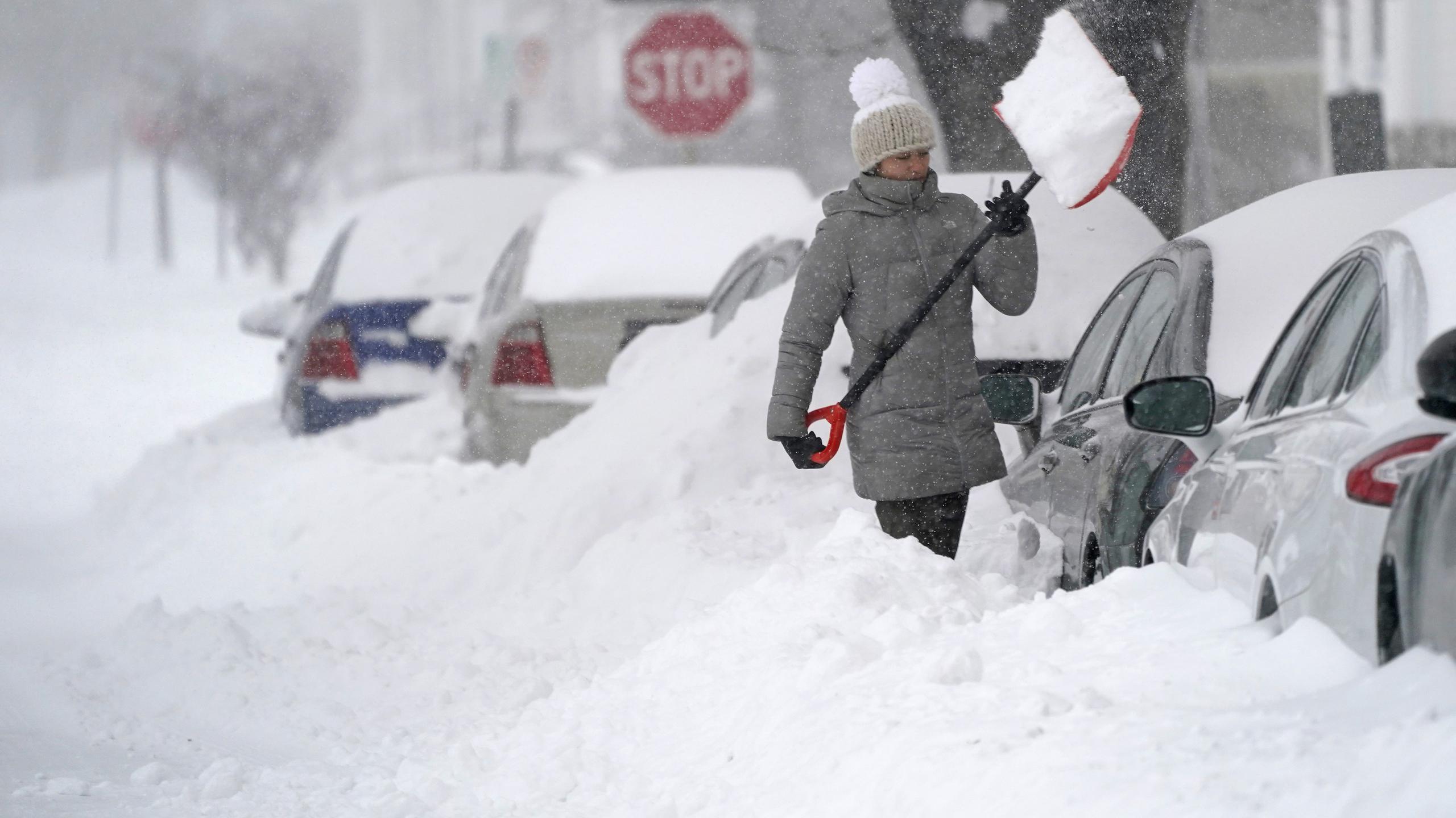 Una mujer lanza una pala llena de nieve para sacar su automóvil en el área de New Hampshire.