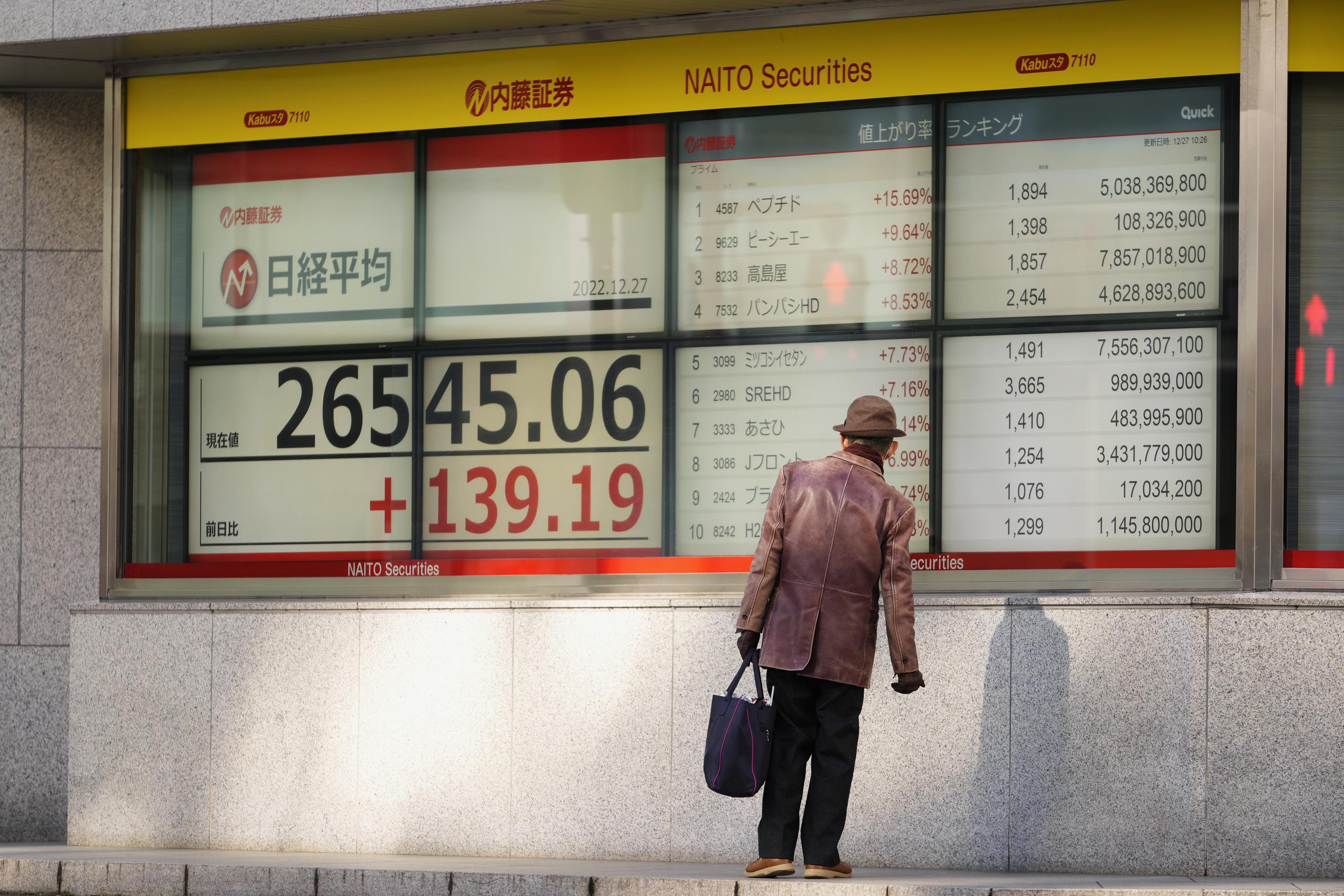 Un hombre revisa los precios de las acciones en el índice Nikkei 225 de Tokio en una firma de inversiones en Japón.