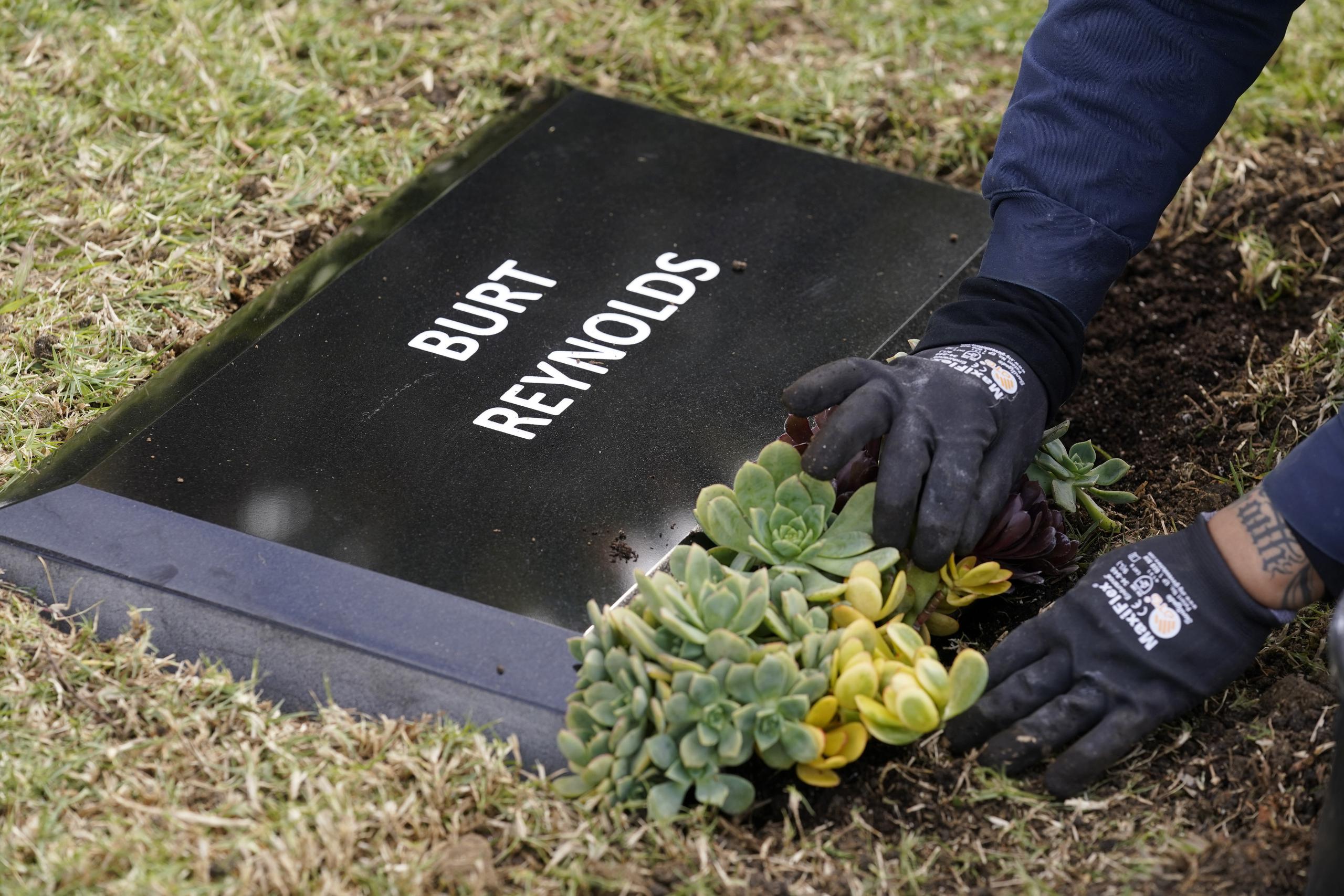 Un trabajador coloca flores frente a una lápida temporal para el difunto actor Burt Reynolds en la sección Jardín de Leyendas del cementerio Hollywood Forever.