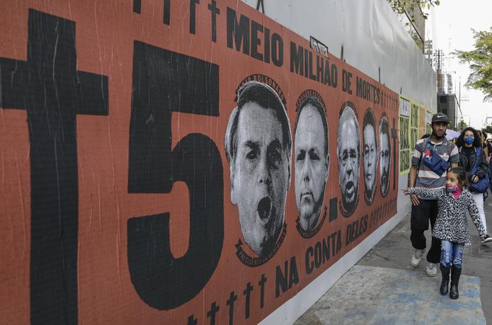 Una niña señala un mural con el rostro del presidente brasileño Jair Bolsonaro durante una protesta por su manejo de la pandemia del COVID-19 en la avenida Paulista, en Sao Paulo, Brasil, el sábado 19 de junio de 2021. (AP Foto/Marcelo Chello)