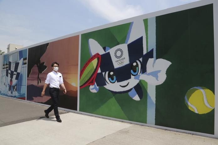 Un hombre camina frente a murales que promueven los Juegos Olímpicos, que están programados a iniciar en julio de 2021.