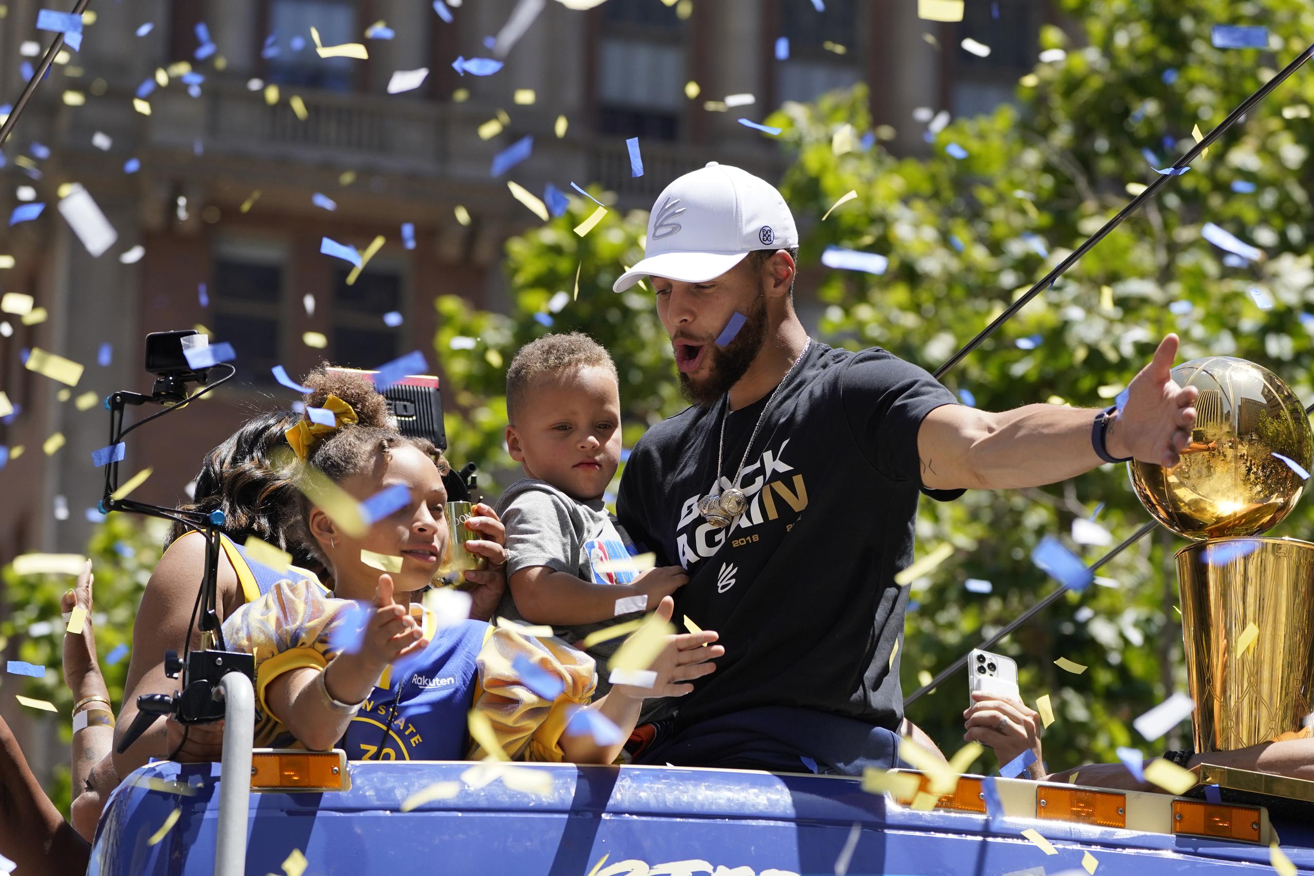 Stephen Curry saluda en medio del confeti azul y dorado, mientras recorre las calles de San Francisco en el desfile de celebración del campeonato de la NBA de los Warriors de Golden State.