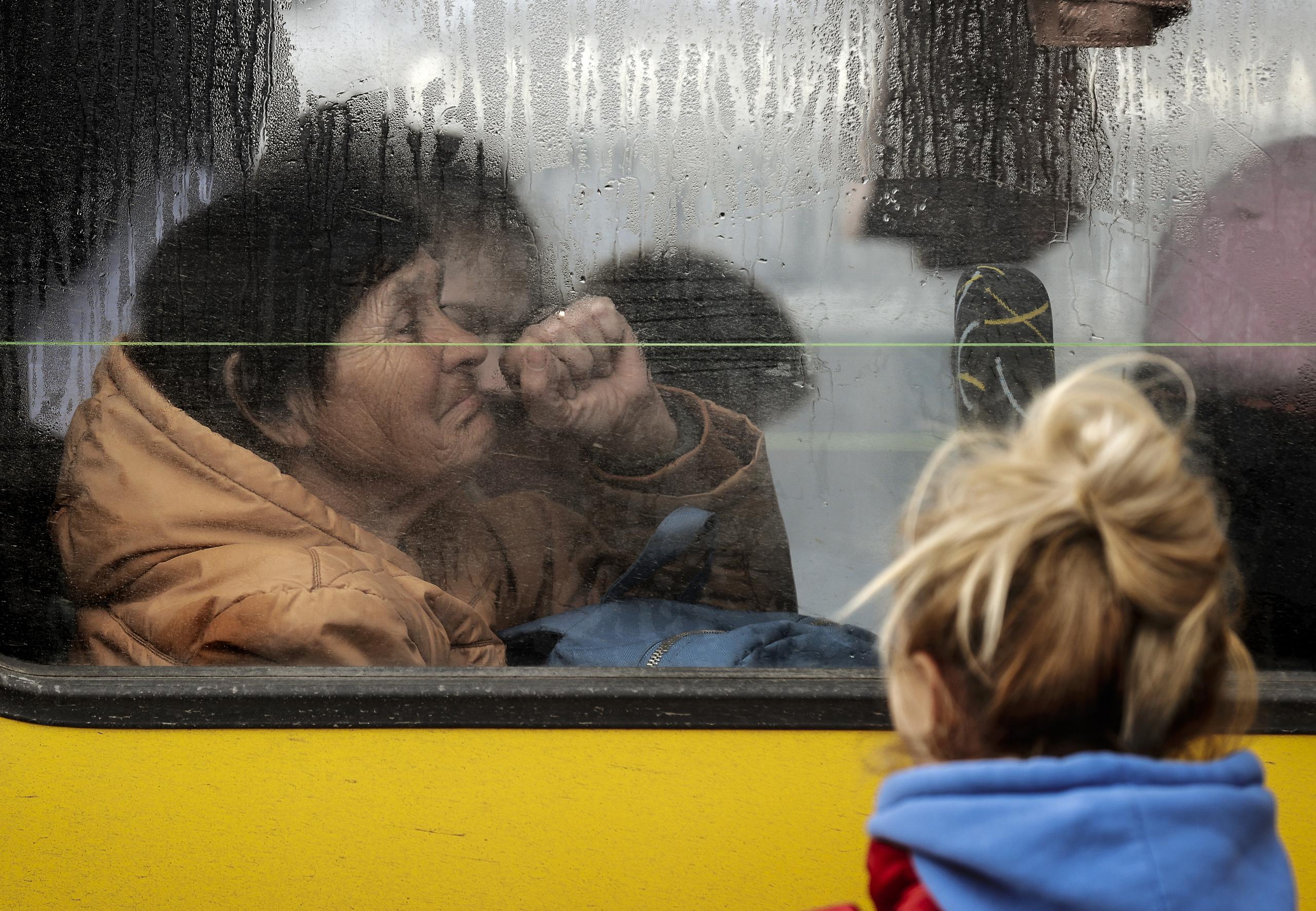 Una mujer hace un gesto en el autobús en el que ha llegado a Zaporiyia. Esta ciudad del centro este de Ucrania se ha convertido en el lugar al que llegan la mayor parte de personas que huyen de Mariúpol y las localidades cercanas controladas por el ejercito ruso. EFE/Manuel Bruque
