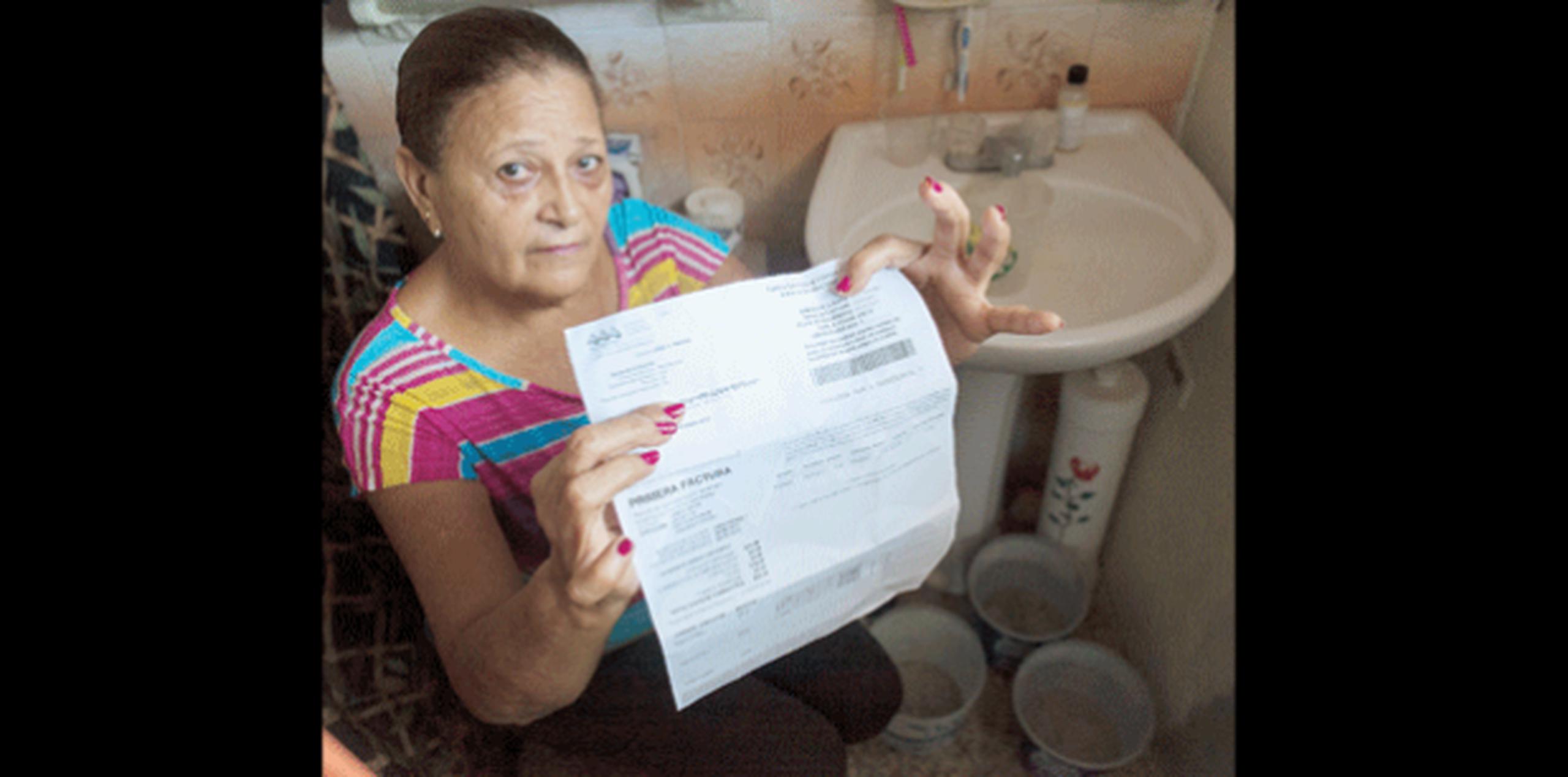 Norma Dávila, vecina de Panaini, muestra su factura de la AAA. Al momento de la foto, no contaba con el servicio de agua. (Para El Norte / Alvin J. Baez)