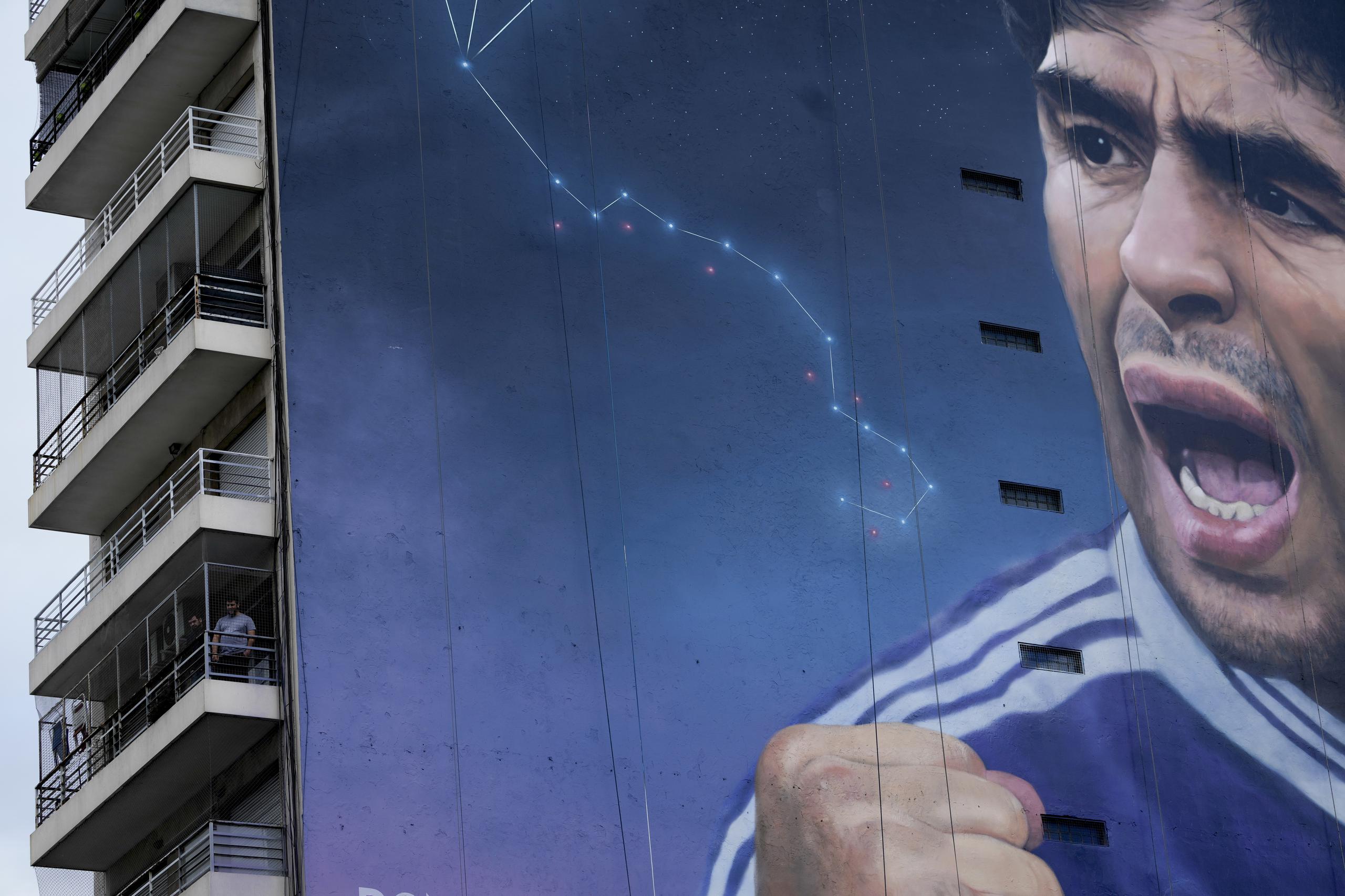 Gente en los balcones en el edificio con un mural de Diego Maradona del artista Martín Ron en Buenos Aires, Argentina, el domingo 30 de octubre de 2022.(AP Foto/Rodrigo Abd)