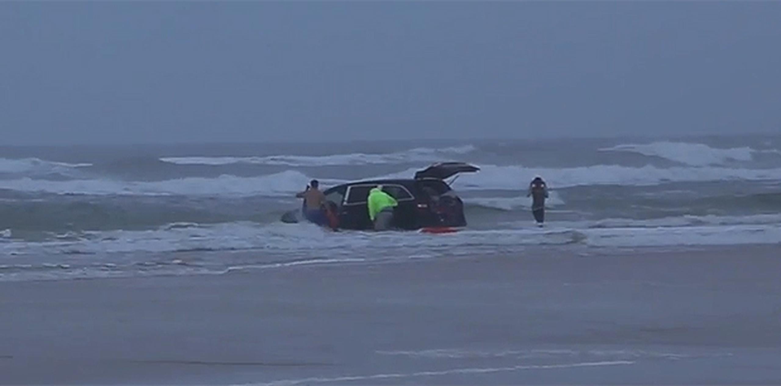 Se aprecia en el vídeo, grabado ayer por la tarde, a un socorrista saliendo del mar con dos niños en sus brazos mientras la parte delantera del vehículo se hunde en el mar. (YT)