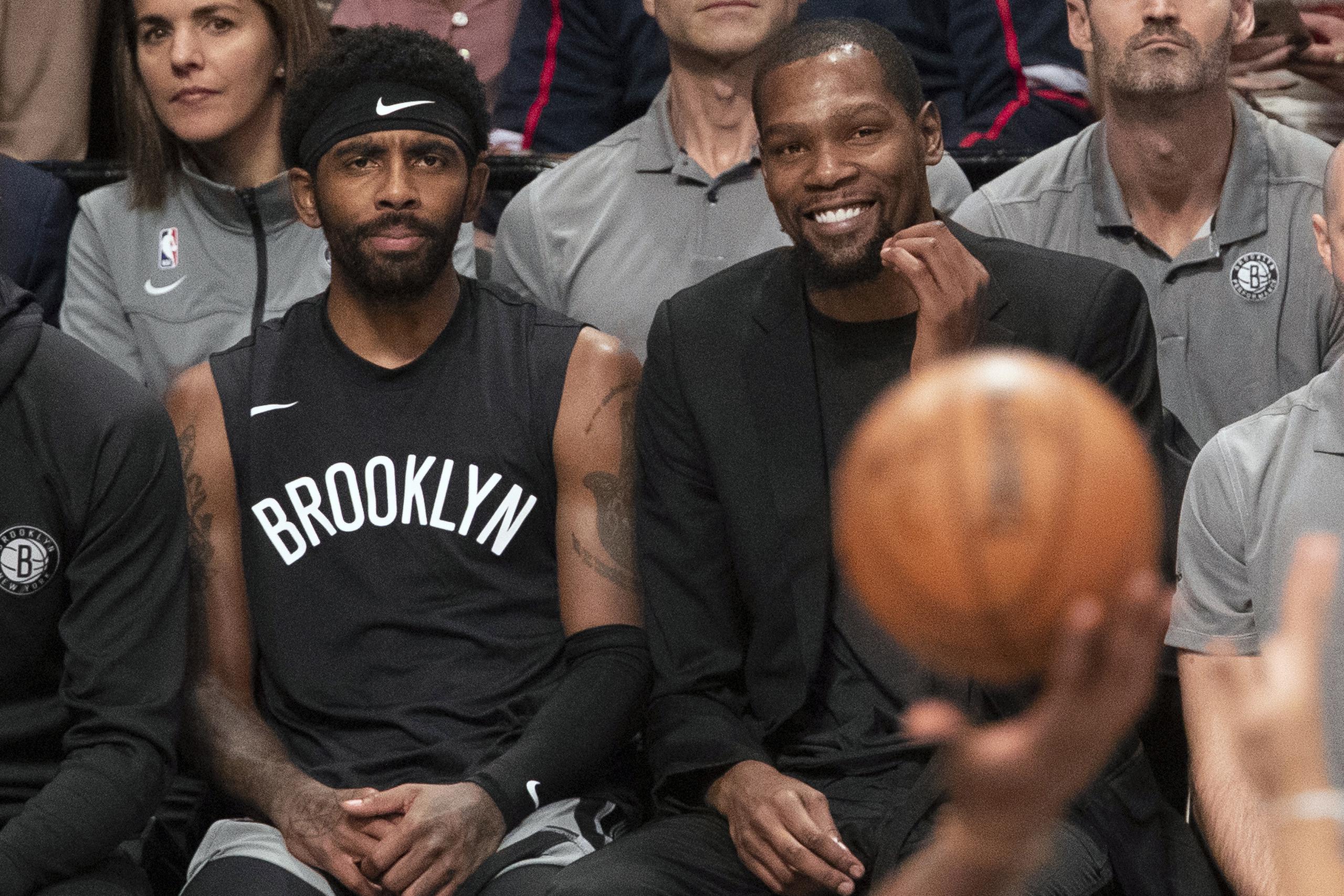 En esta foto del 1 de noviembre de 2019, Kyrie Irving (izquierda) y Kevin Durant de los Nets de Brooklyn observan un partido contra los Rockets de Houston en Nueva York.