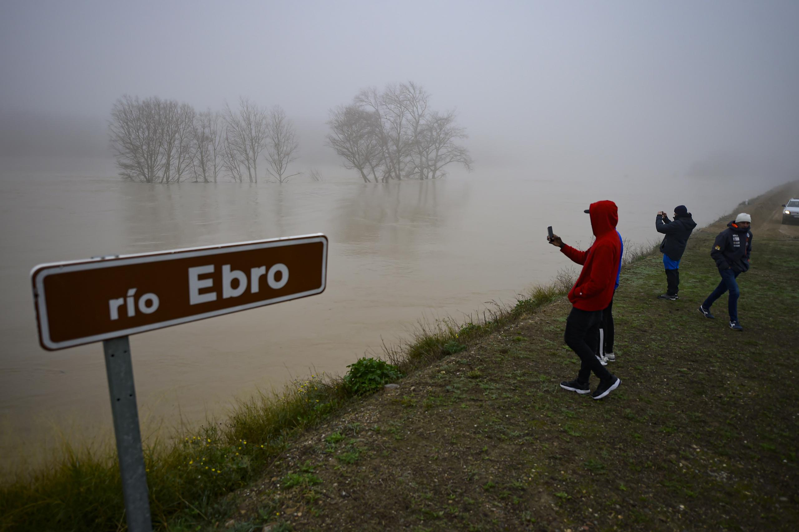 Personas en la zona inundada cerca del río Ebro en el pequeño pueblo de Pradilla de Ebro, provincia de Aragón, en el norte de España, el lunes 13 de diciembre de 2021. Las fuertes lluvias provocaron inundaciones en el norte de España. (Foto AP / Alvaro Barrientos)