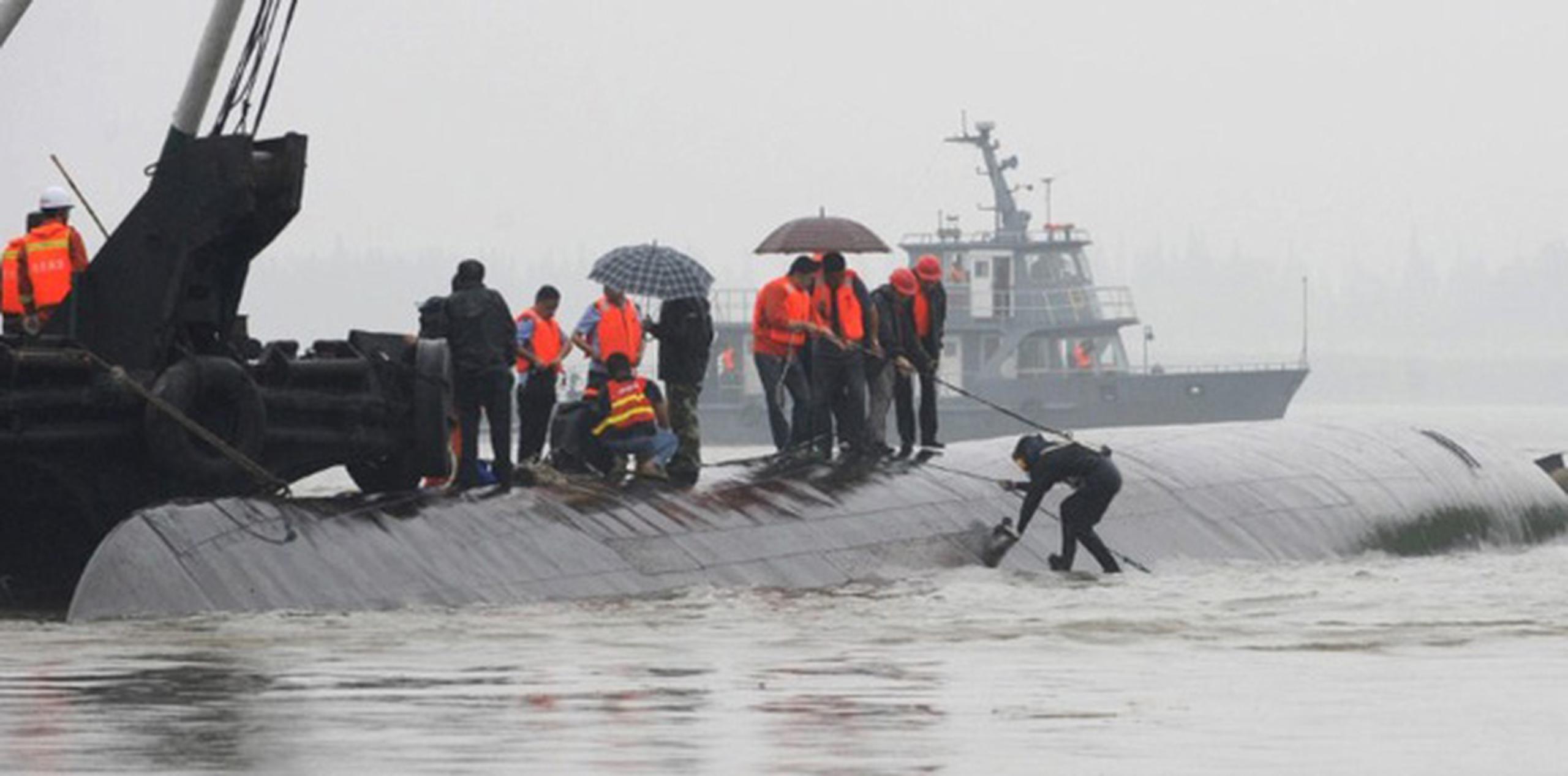 Las imágenes de televisión mostraban a rescatistas con chalecos naranjas trepando al barco que quedó boca abajo. (AFP)