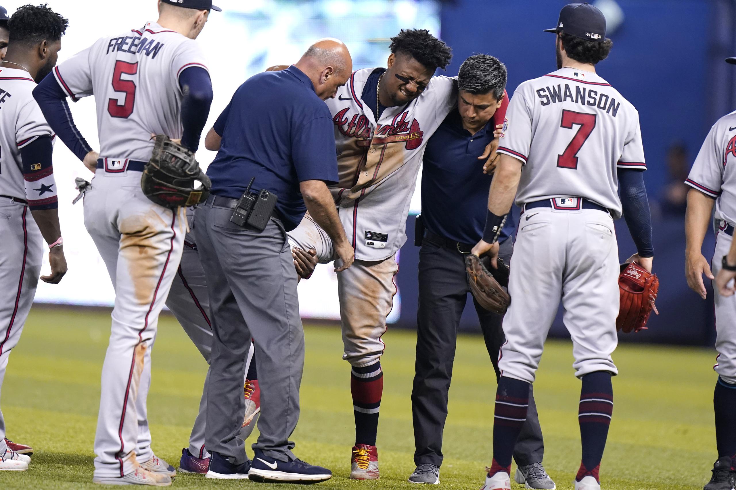 Ronald Acuña Jr., de los Braves de Atlanta, derrama lágrimas de dolor mientras es ayudado a salir del terreno de juego el sábado en Miami.