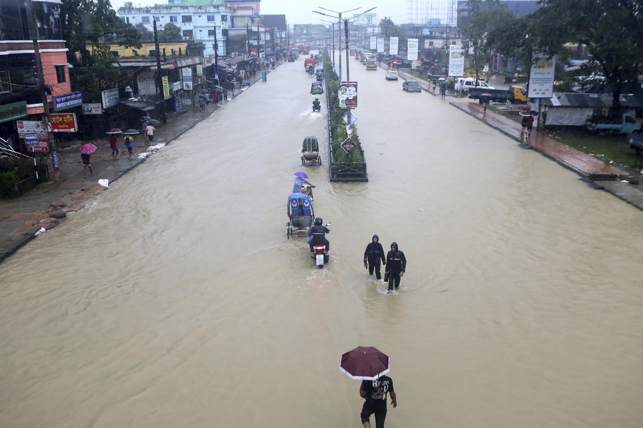 Personas caminando a través de un área inundada por Sylhet, Bangladesh.